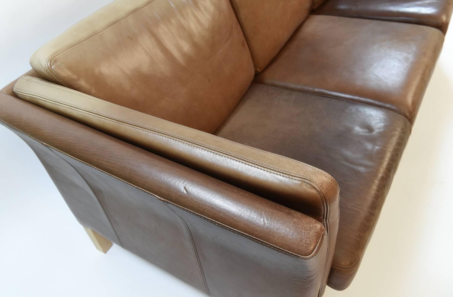 This sofa by Mogens Hansen sits three people comfortably. Upholstered in vintage leather. In the manner of Danish midcentury designer Børge Mogensen.