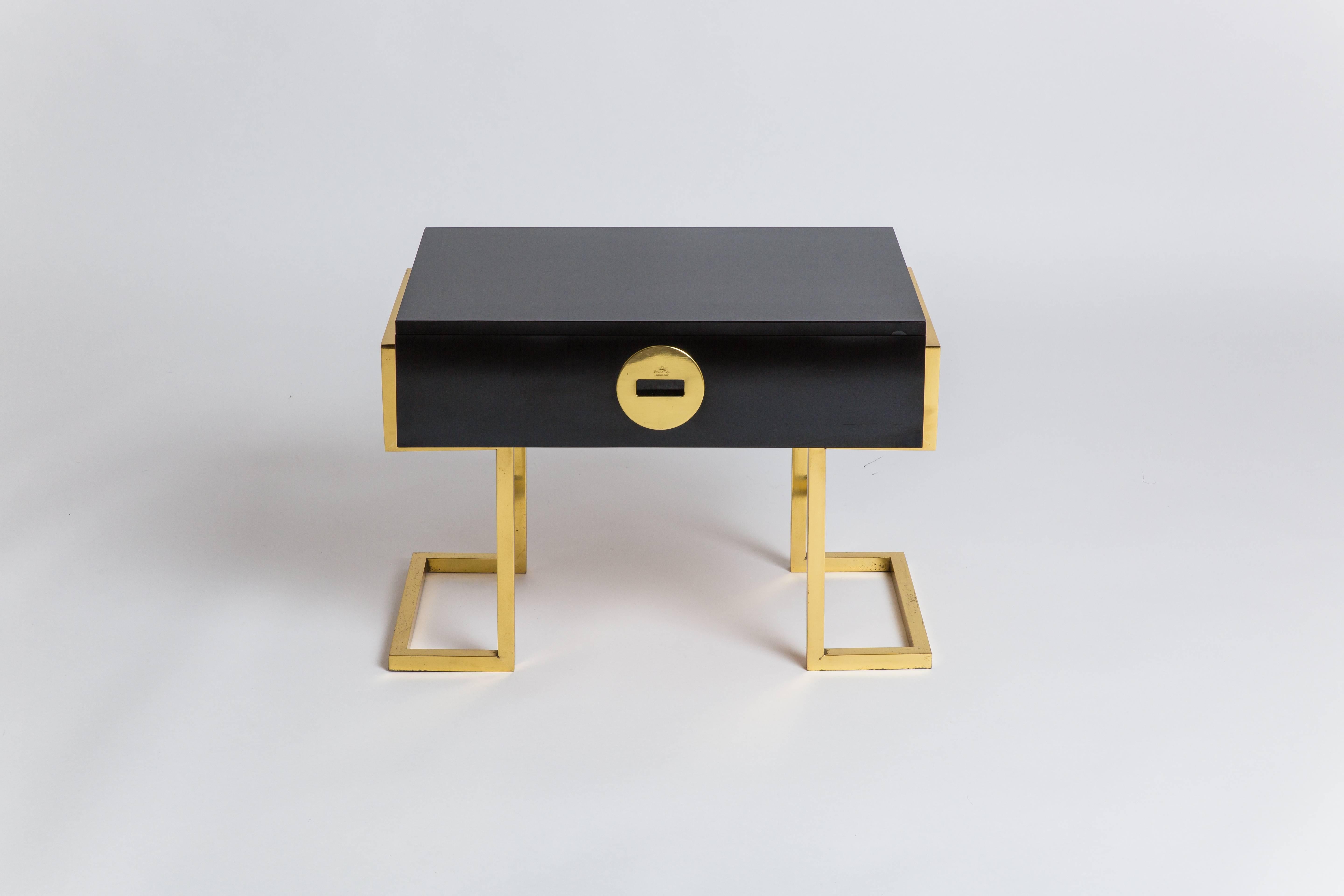 Romeo Rega pair of rare black laminate end or bedside tables with single drawers and architectural brass legs, Italy, 1970s. Each signed on manufacturer’s brass roundel 'Romeo Rega/Made in Italy.'  
These chic sculptural tables are in great original