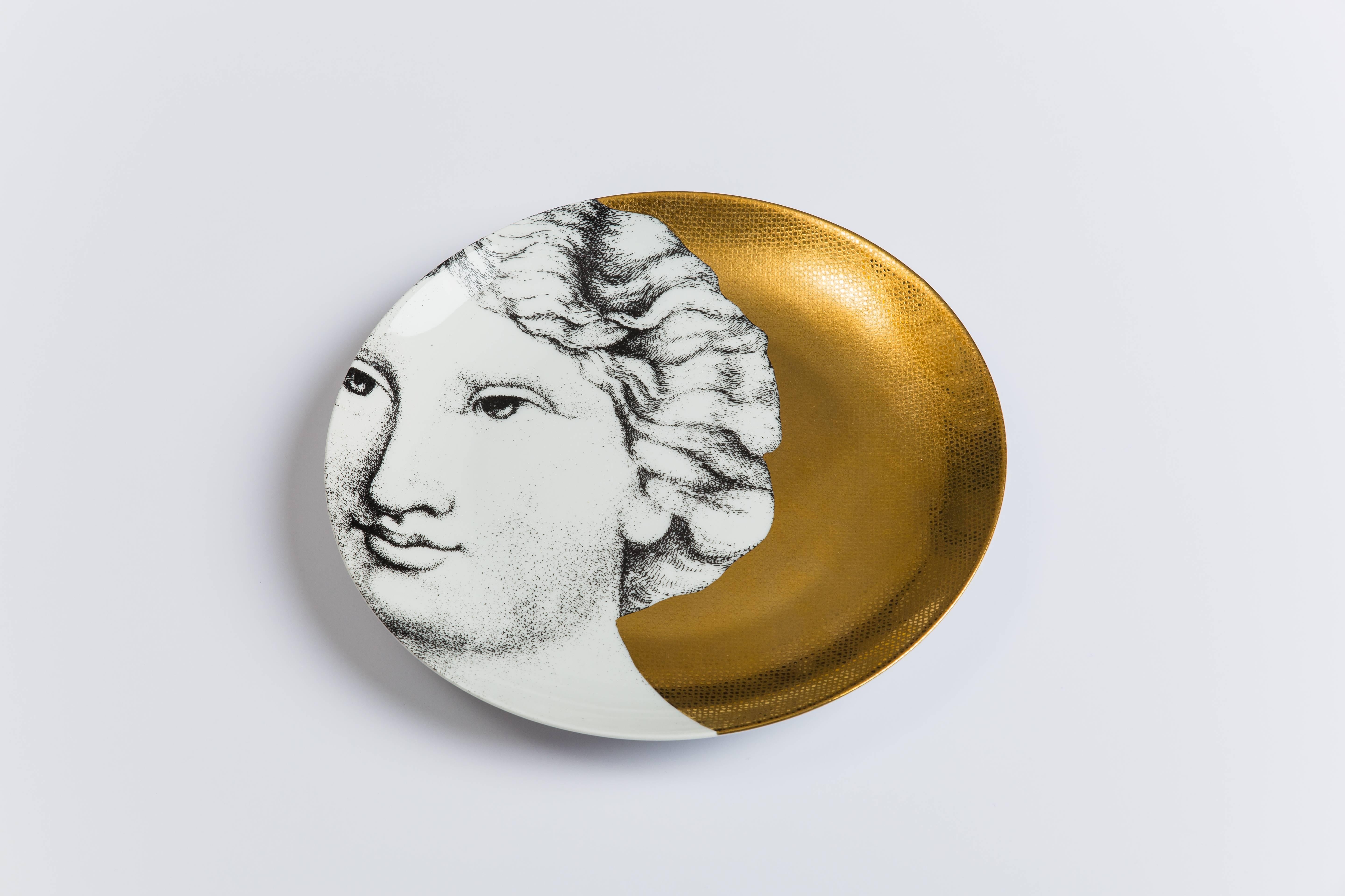 Porcelain plates with lithographic transfer-printed decoration on a vibrant and elegant gold ground, comprised of 12 ‘Adam’ and 12 ‘Eve’ plates. Each plate numbered and printed with designer’s marks 'FORNASETTI MILANO MADE IN ITALY' on the reverse.