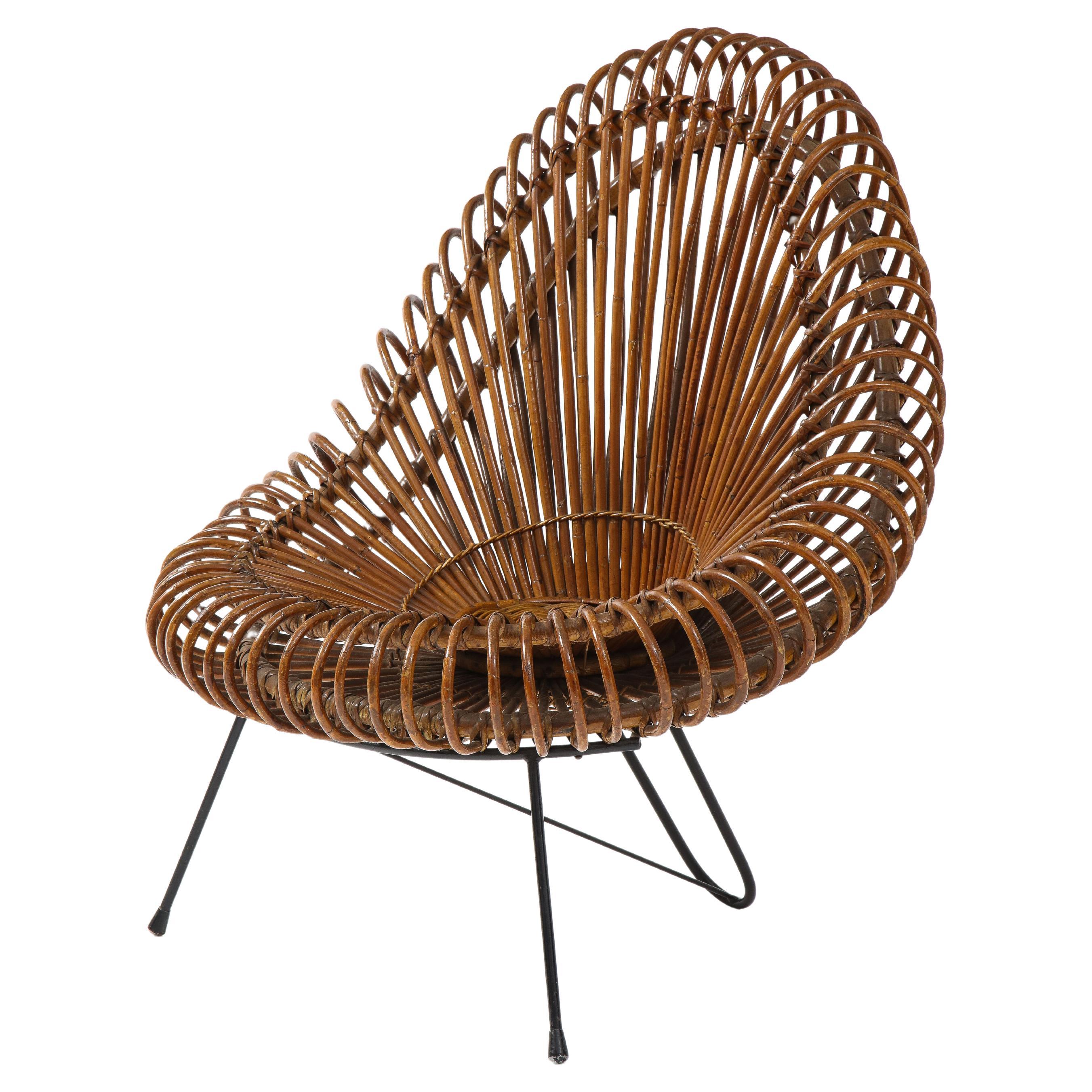 Janine Abraham and Dirk-Jan Rol for Edition Rougier sculptural woven rattan lounge chair on black enameled steel frame and tripod legs with round ivory bouclé cushion, France, 1950s. This iconic basketweave designed lounge chair is beautifully and