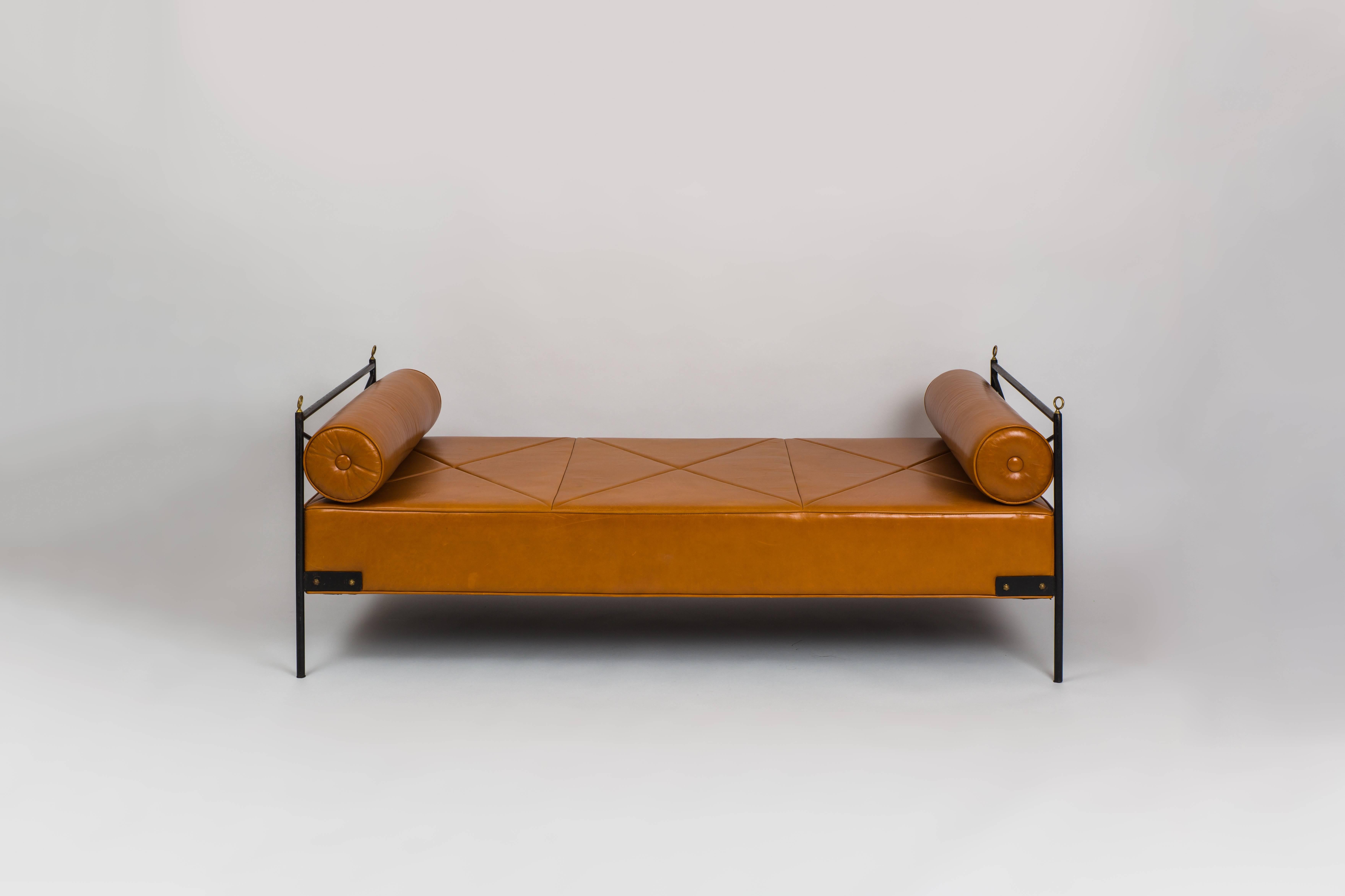André Arbus daybed composed of wrought iron frame with bronze details, upholstered in cognac leather with two bolsters, France, 1940s. Very chic modernist Art Deco design and beautifully crafted with great details in the daybed frame and leather