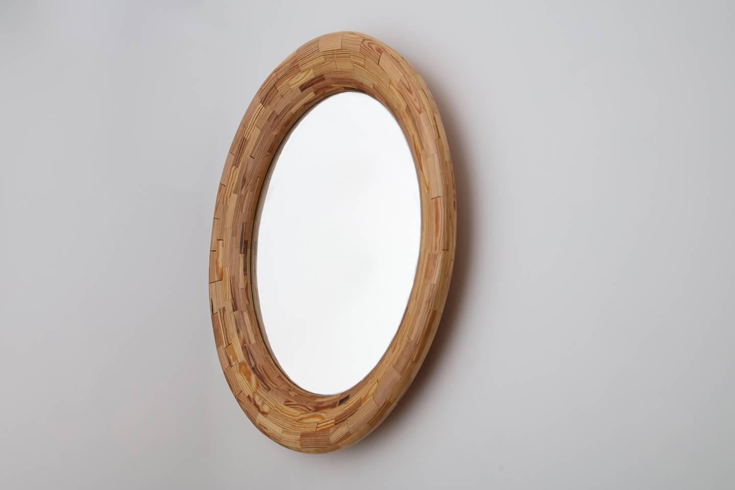 Part of Richard Haining's Stacked Collection, this 24 inch diameter round mirror has a 32-1/2 inch diameter frame made of reclaimed heart pine. The wood was salvaged offcuts from a gutted Brooklyn Brownstone's building joist. The wood's natural