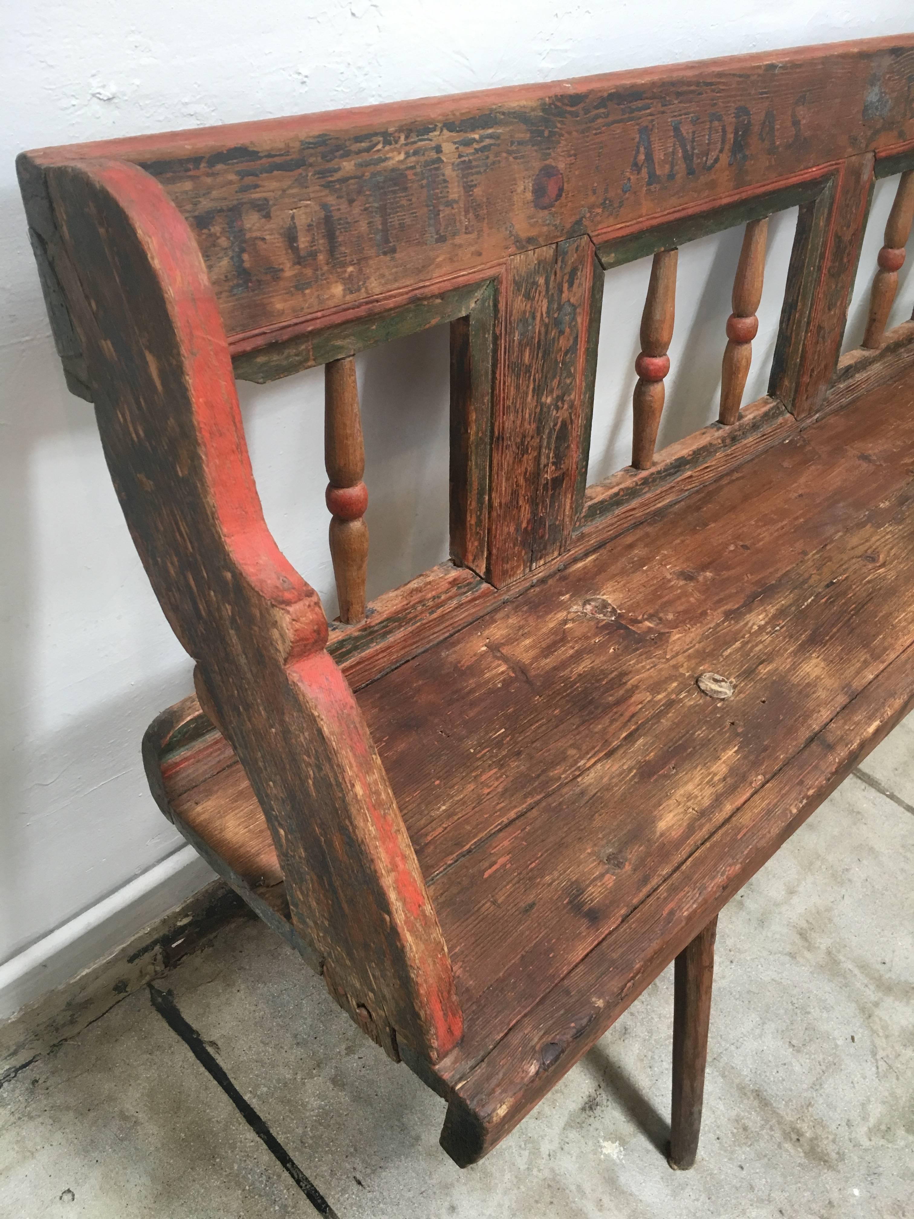 Ornate vintage bench circa 1868. Beautifully weathered paint colors of orange or red and green, and an inscription across the top of the back rest that includes the year.