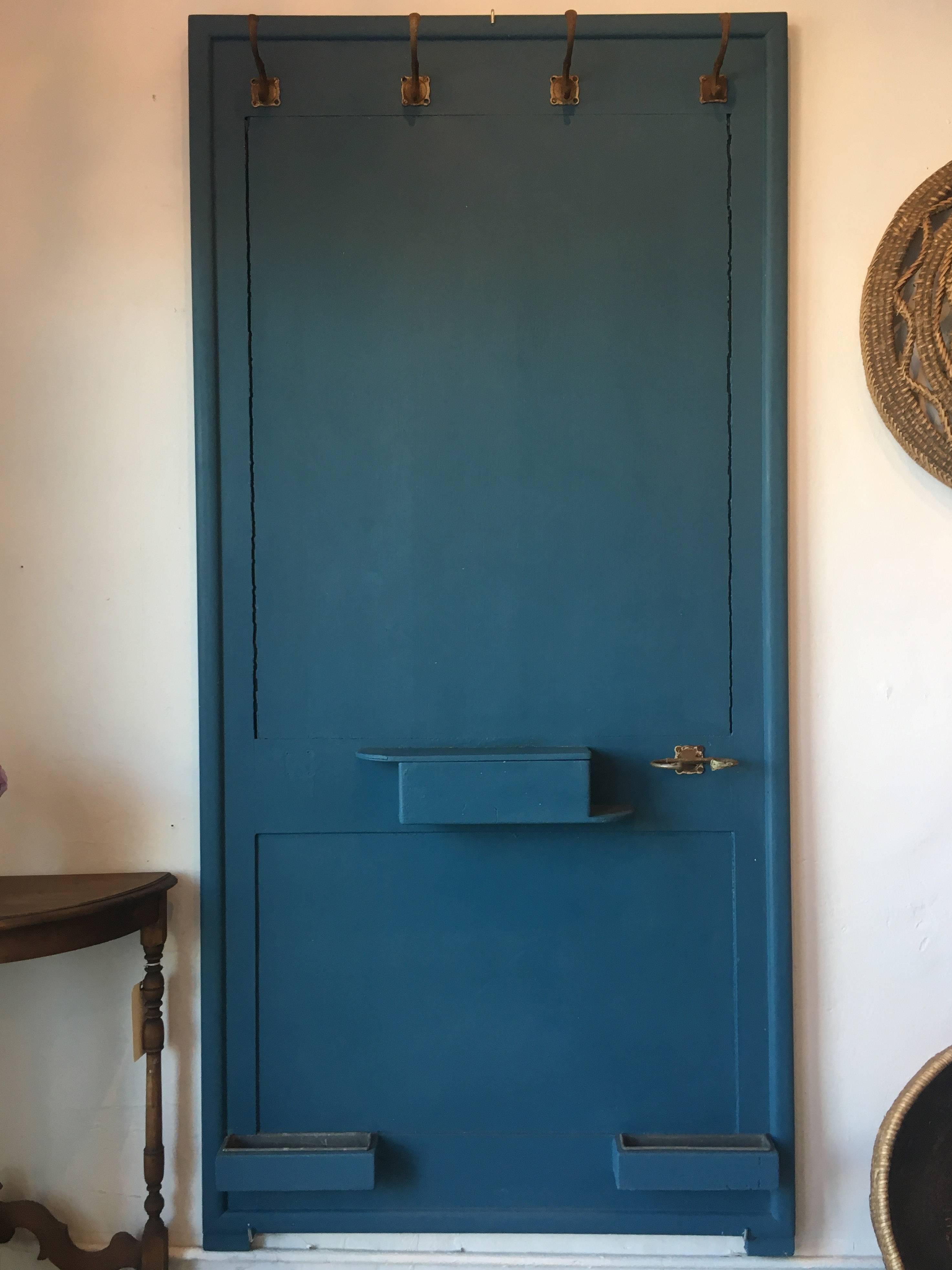 Hallway rack made from a vintage European door. Four hooks along the top, a small shelf and a hook beside it, and two smaller compartments along the bottom. Painted beautiful peacock blue teal color.