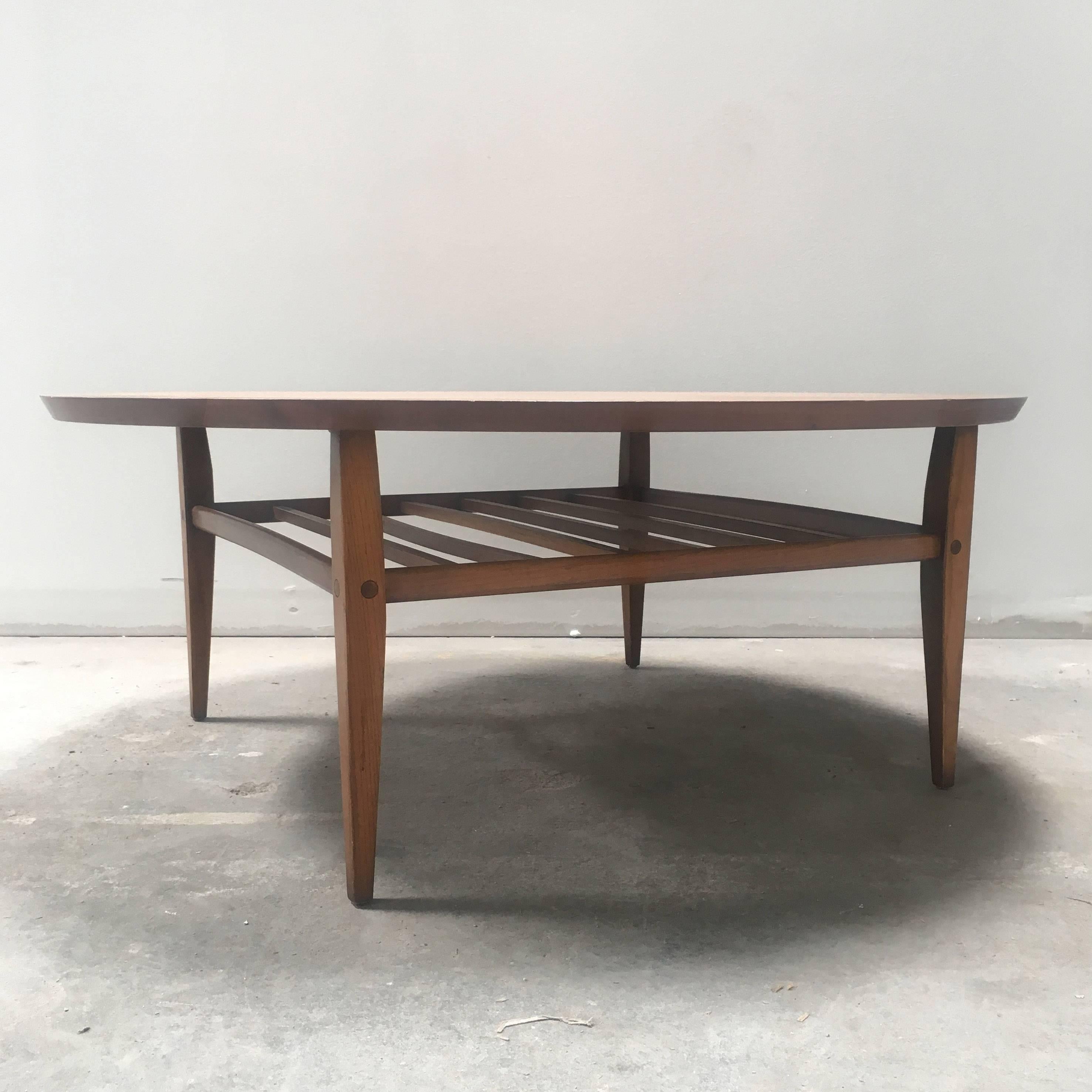 Mid-Century coffee table with slatted shelf underneath the tabletop. Four tapered legs with beautiful ridge details. Label reads 