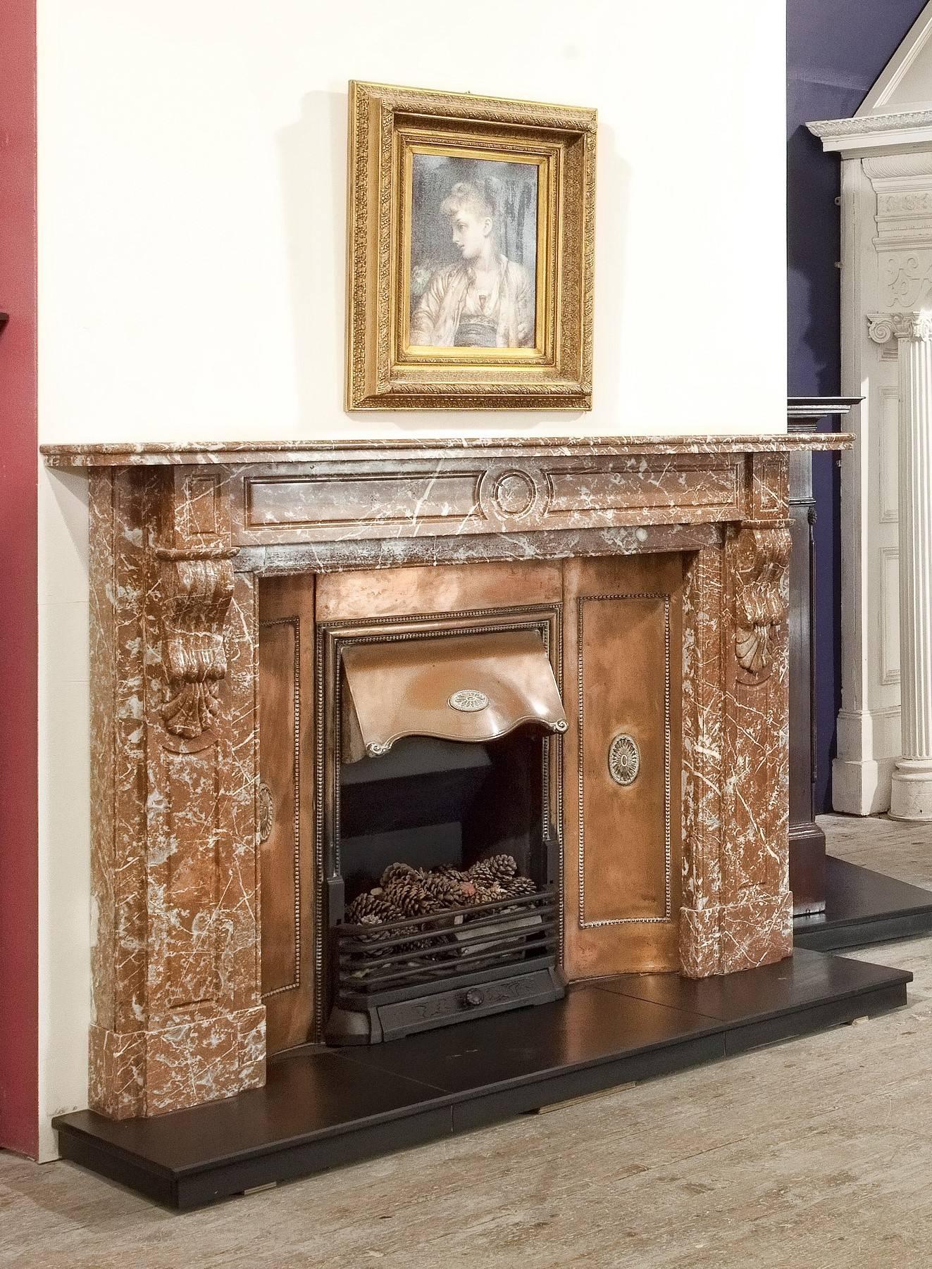 This Victorian breche marble fireplace surround has hand-carved recessed panels on the jambs and frieze with carved centre circle, the carved corbels supports the two-tier mantel. The marble fire surround is complimented with the original interior