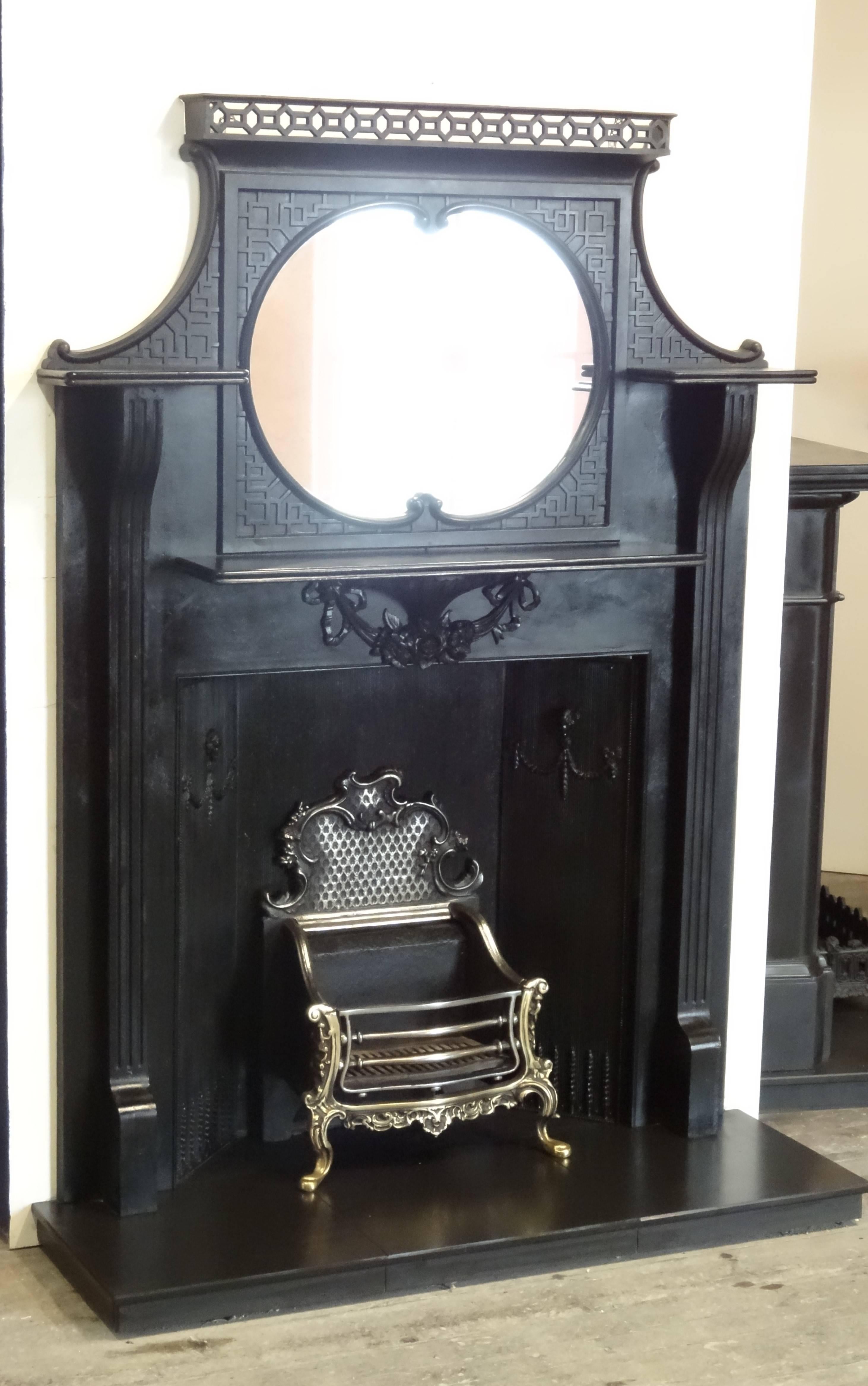 Antique cast iron chimney piece with integral overmantel. The fireplace is complimented with a rare cast iron triple panel fireback featuring ram's head mask.

This fireplace was reclaimed from an Edwardian property in County Down Northern Ireland.