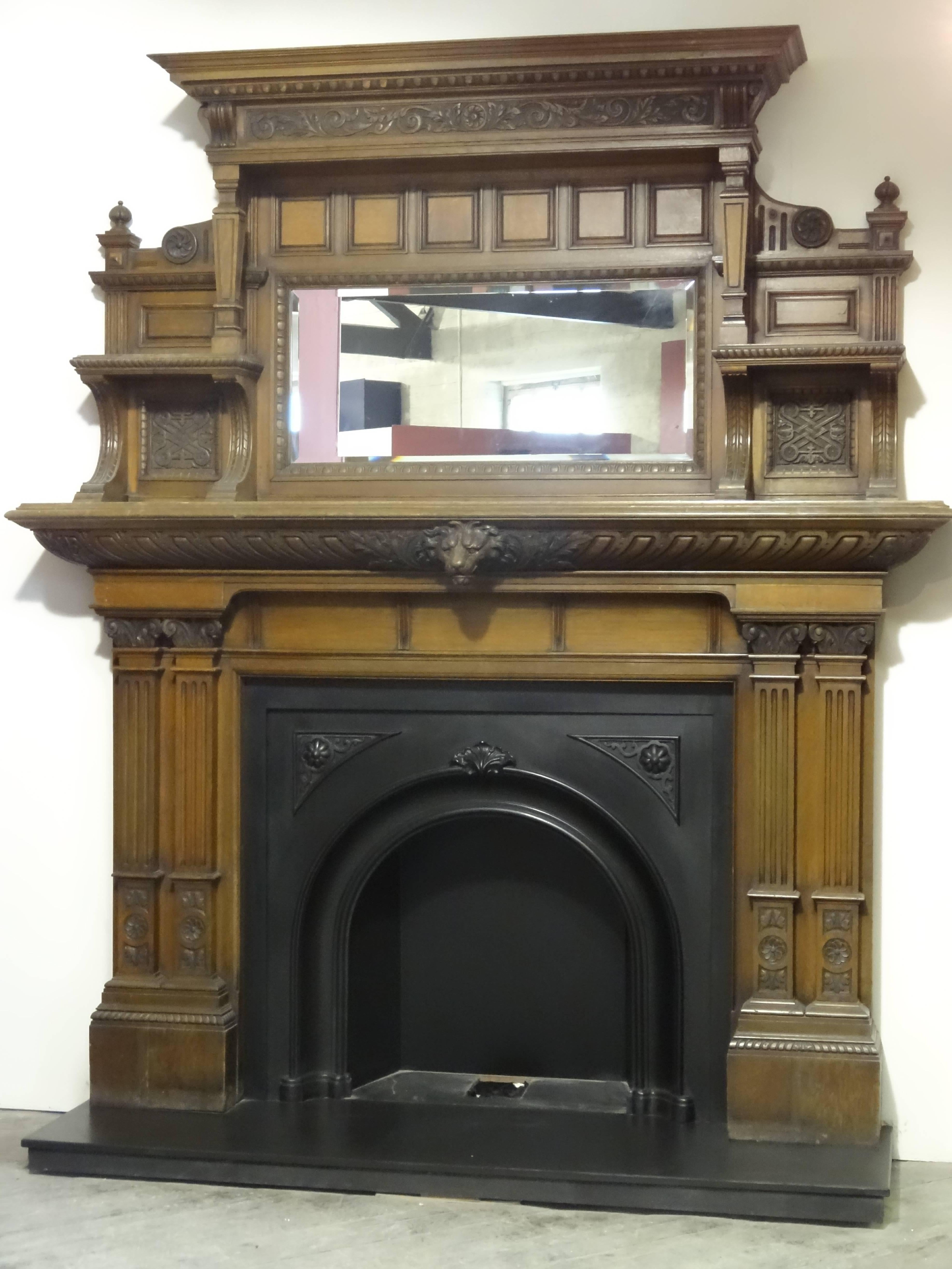 Reclaimed antique Victorian ornately carved oak fire surround and overmantel mirror, with impressive carved lion's head mask. The fire surround is complimented with the antique Victorian arched cast iron insert suitable for freestanding dog grate