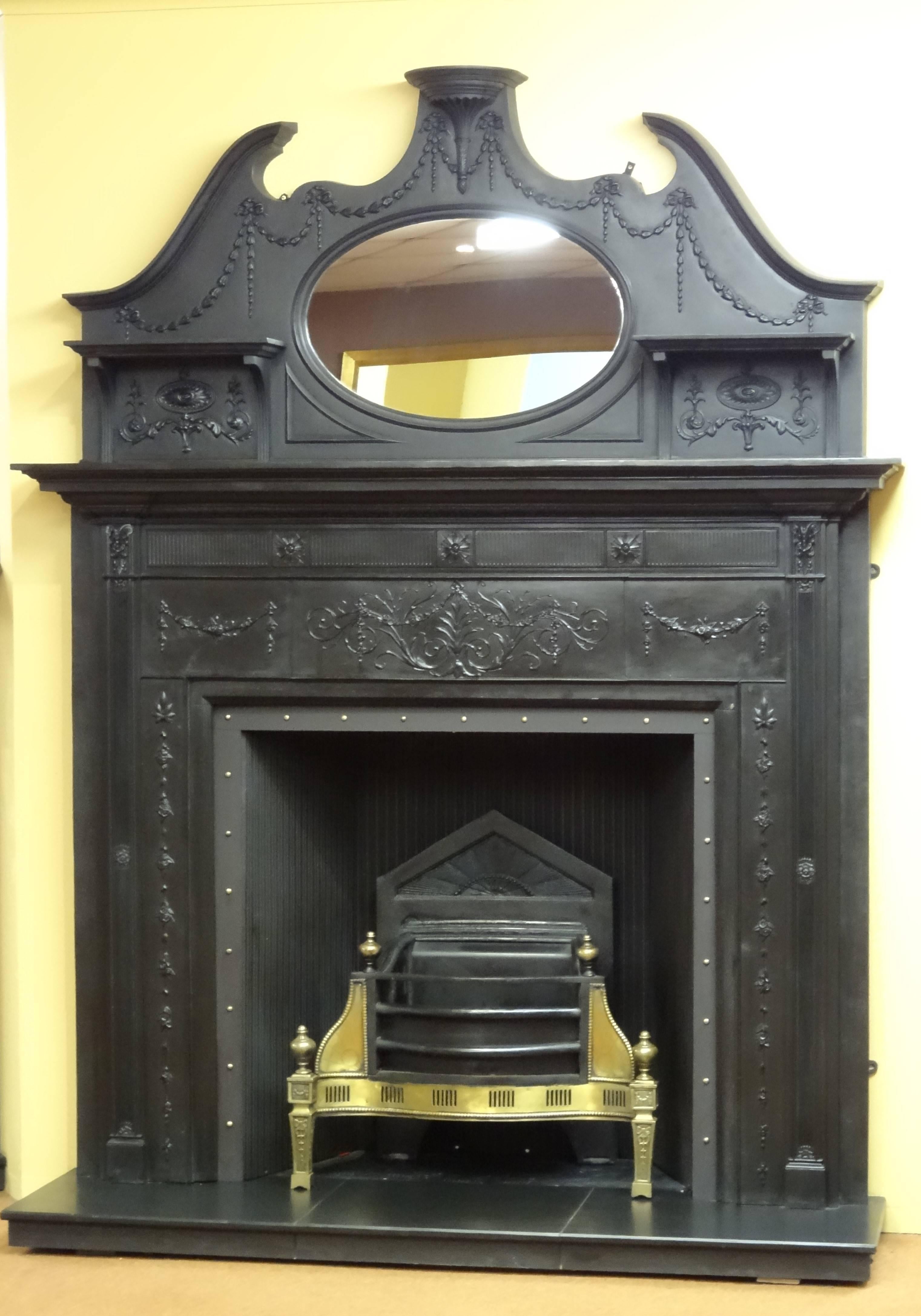 19th century Victorian cast iron fireplace surround and matching overmantel mirror. This fireplace is complimented with 20th century cast iron reeded panelled fireback and brass studded metal trim. This fireplace was reclaimed from a Victorian