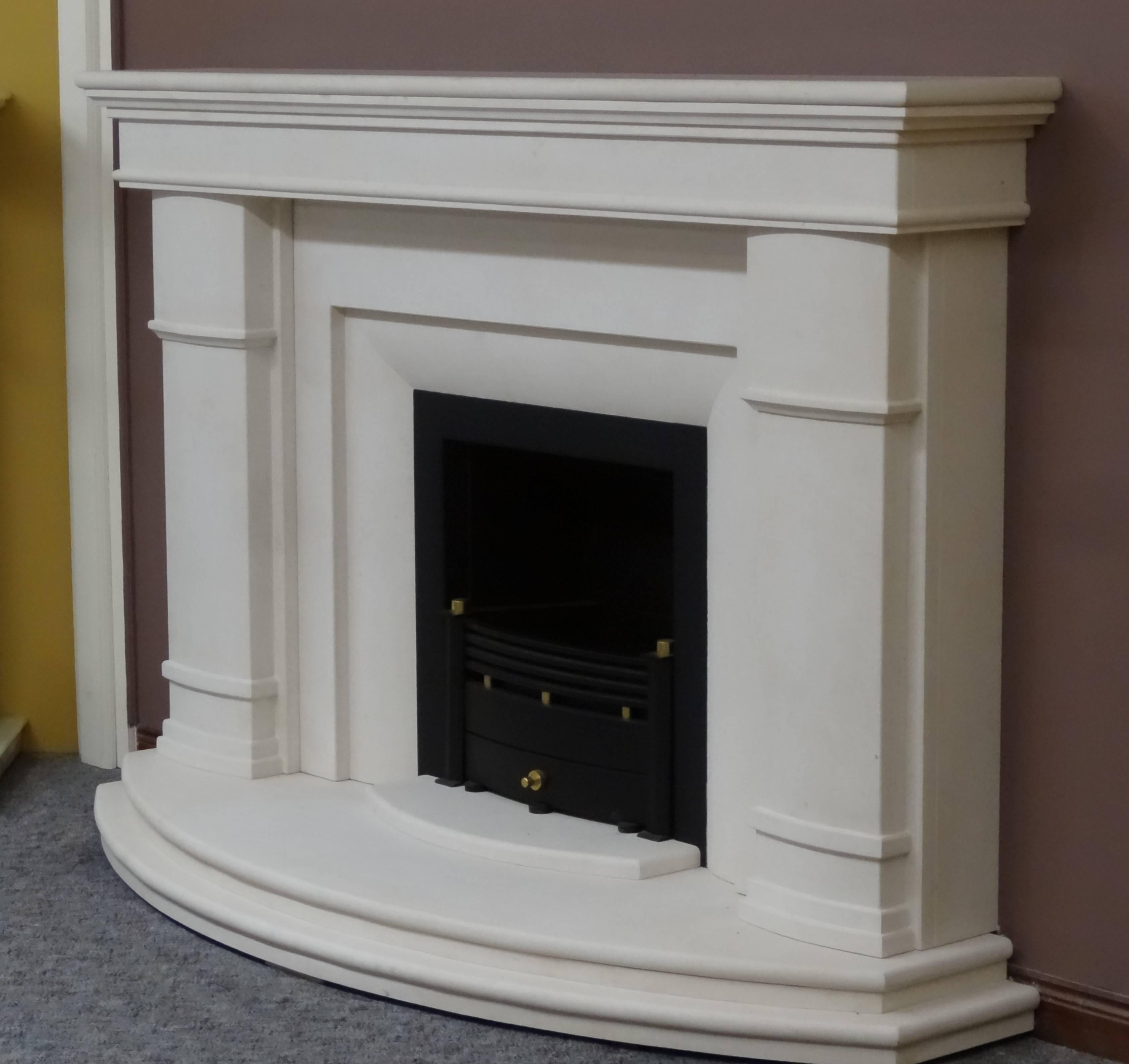 We created this fireplace from honed Portuguese limestone. The fireplace features curved hearths, jambs and insert. Fireplace comprises matching curved hearths, black metal trim built in to the insert and the removable black and brass fire