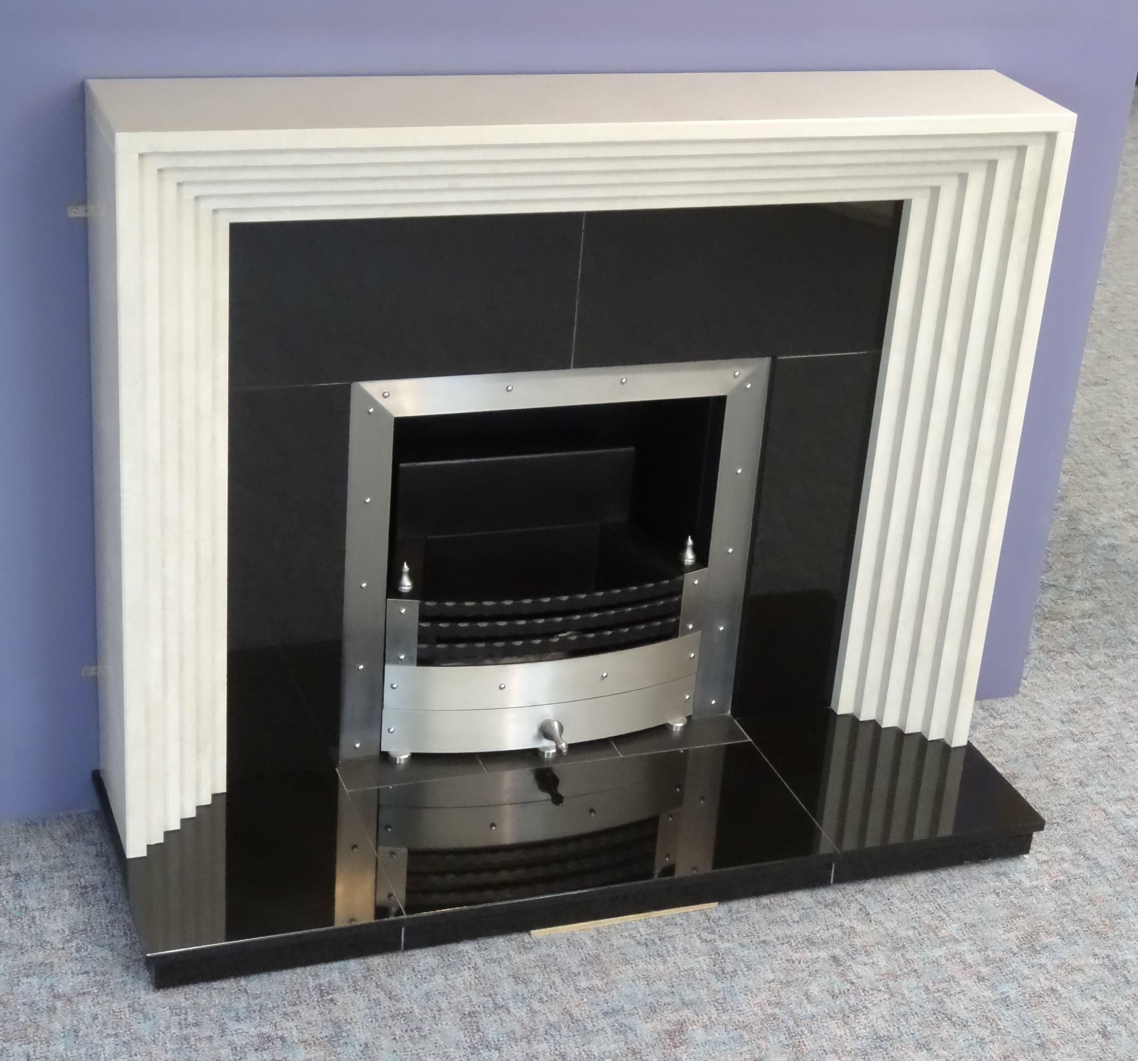 We created this Art Deco fire surround from polished Greek Goran marble. The fireplace comprises of polished black granite hearth and insert, the brushed steel frame is built in to the
granite insert, the matching steel fire basket is