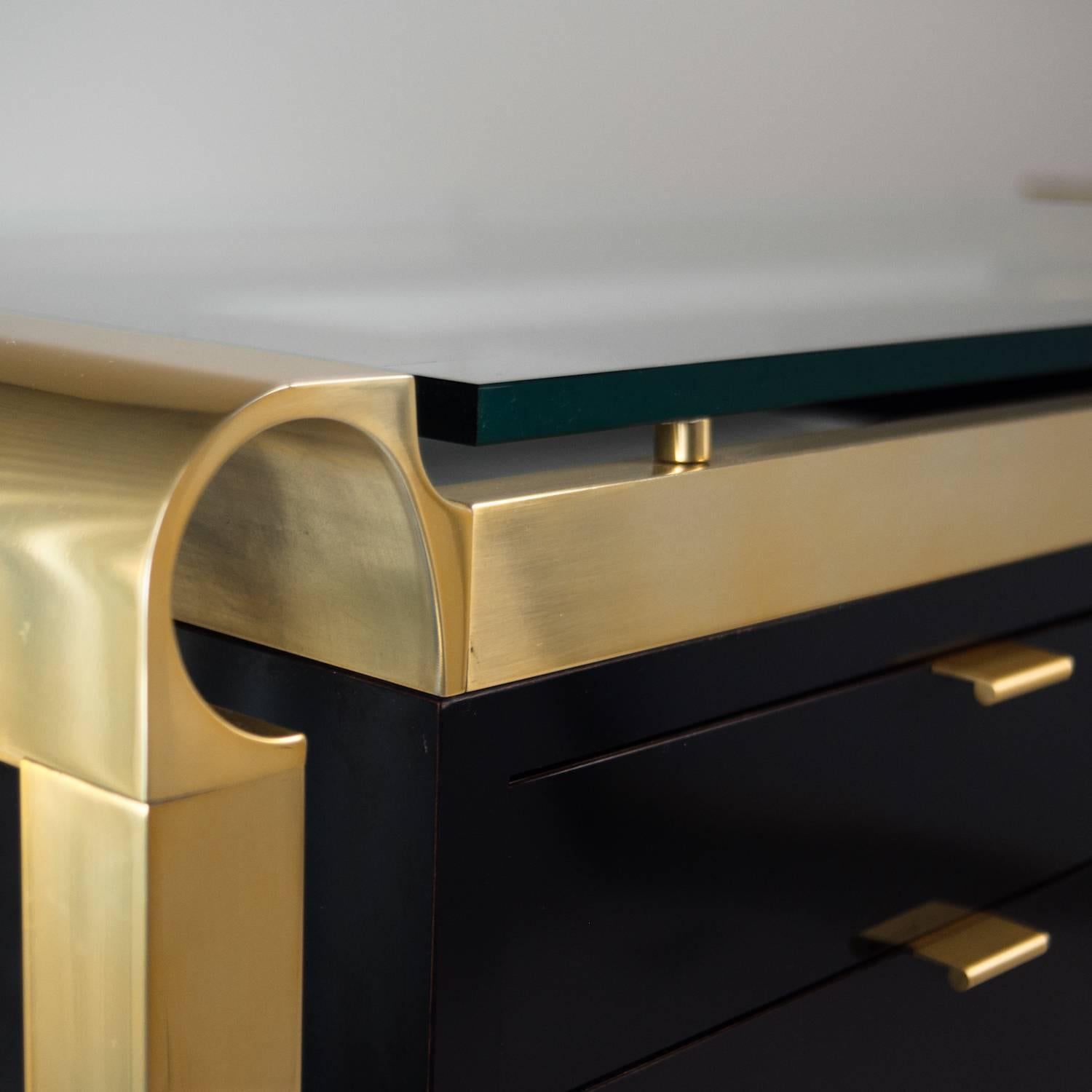 Black laminate desk in the style of Pace Collection. Metal frame is finished in brass, glass top is a half inch thick.