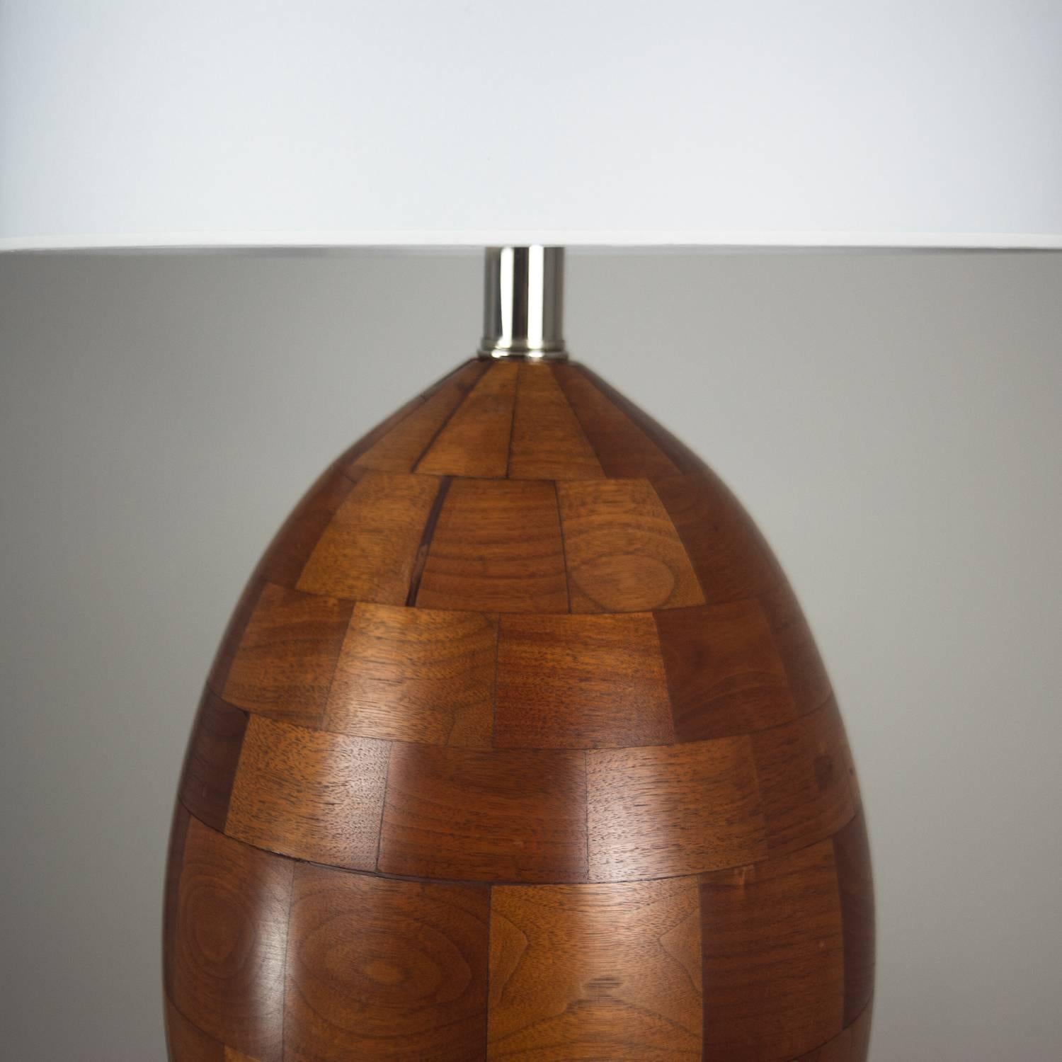 Egg shaped walnut lamp made of staved walnut blocks with clear satin finish. Professionally rewired with black silk cord and new lamp shade. 

Shade measures 14