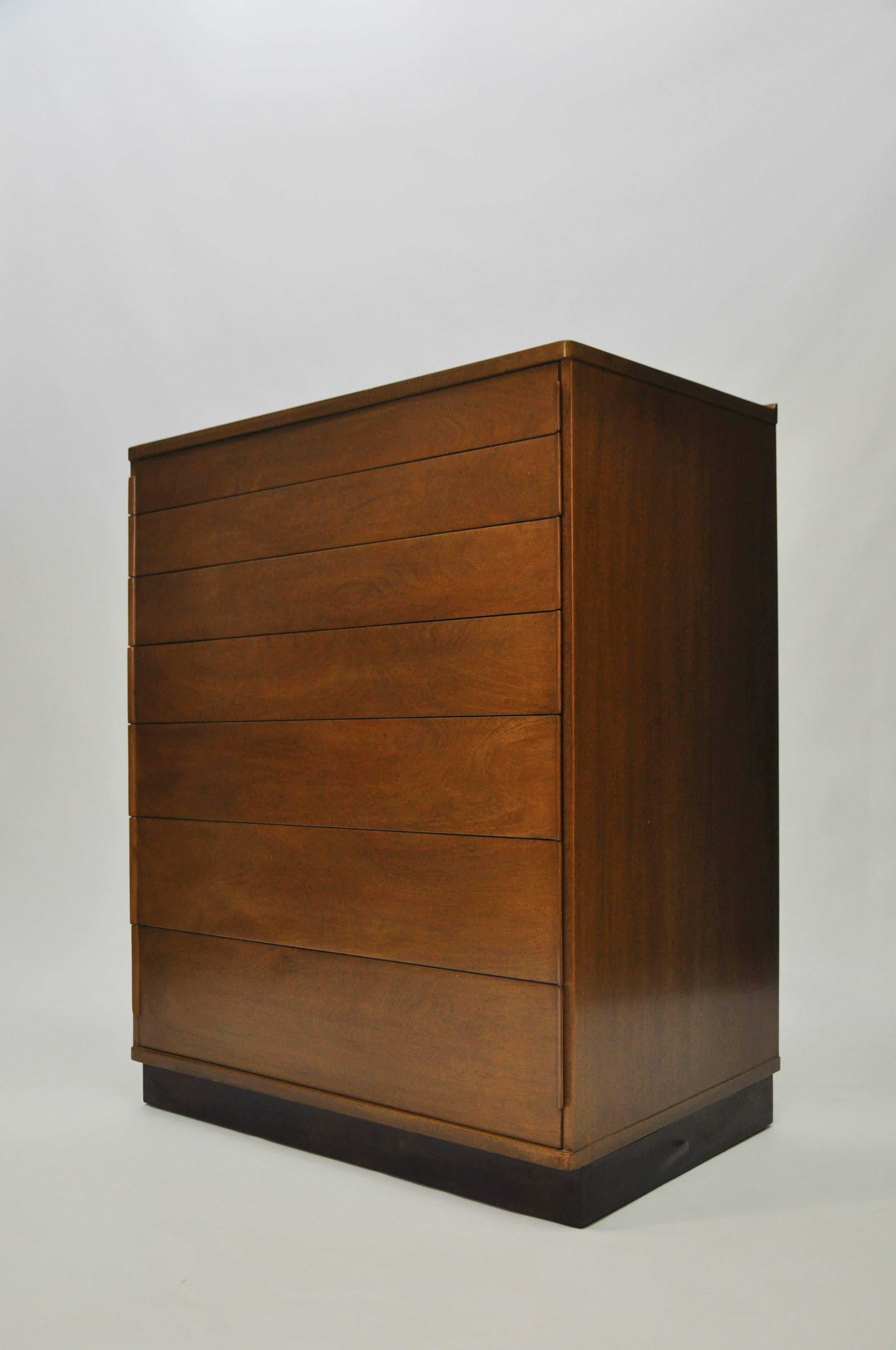 Late 1950s Dunbar seven-drawer chest by Ed Wormley. Warm medium brown walnut finish. Solid oak secondary wood is used for the drawers, which are dovetailed on all four corners. Leather wrapped base. The back of the top has a flared edge, which