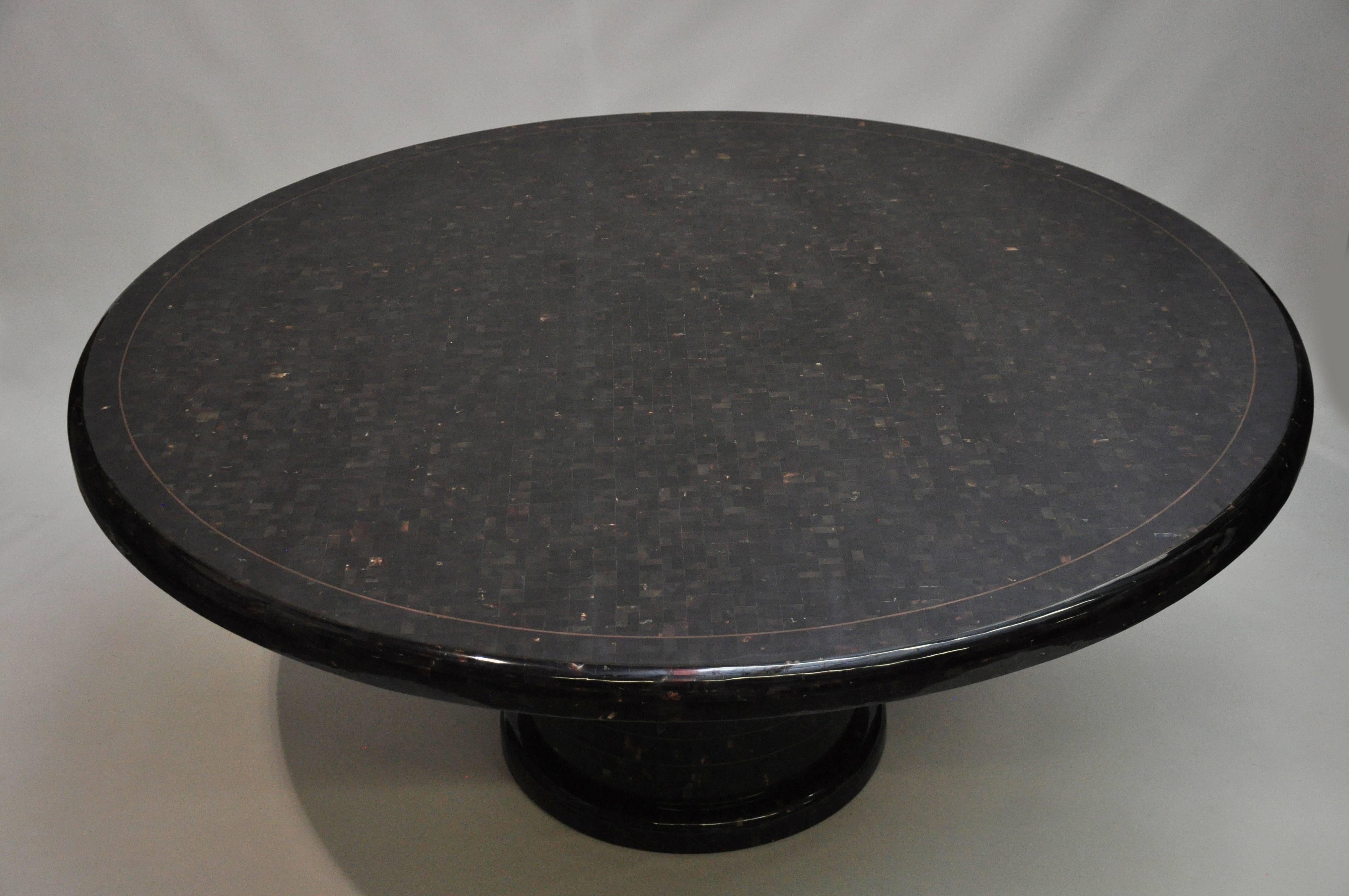 Striking round penshell table by Maitland-Smith. The entire surface is covered in polished mollusk shell tiles, which are a rich, mottled, dark brown color. A narrow inlaid band on the top creates a nicely refined detail next to the bull-nose edge.