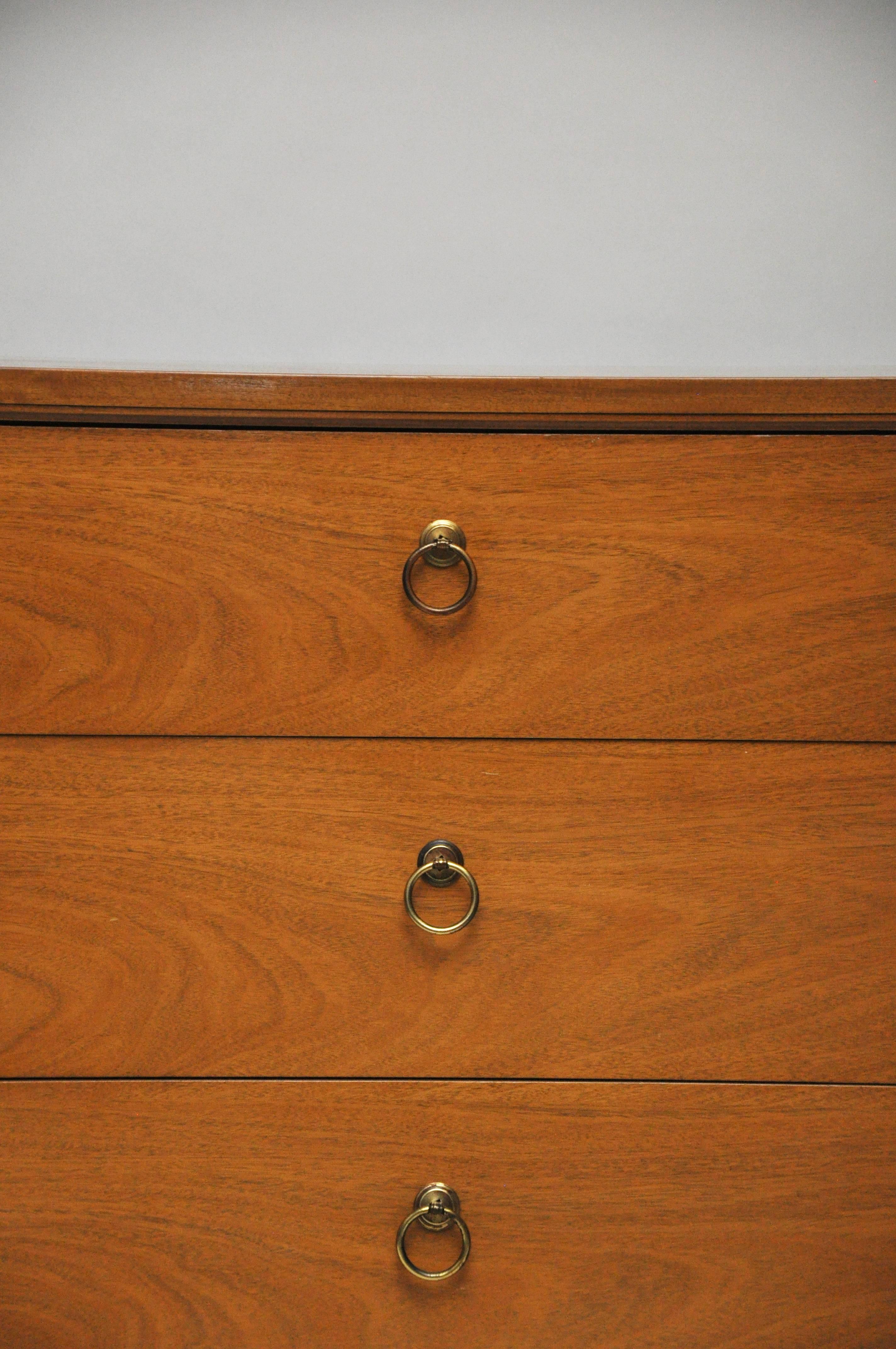 Kent-Coffey three-drawer small dresser with brass hardware. This is made of light walnut veneer. Chest is on tapered legs with brass strip detail.