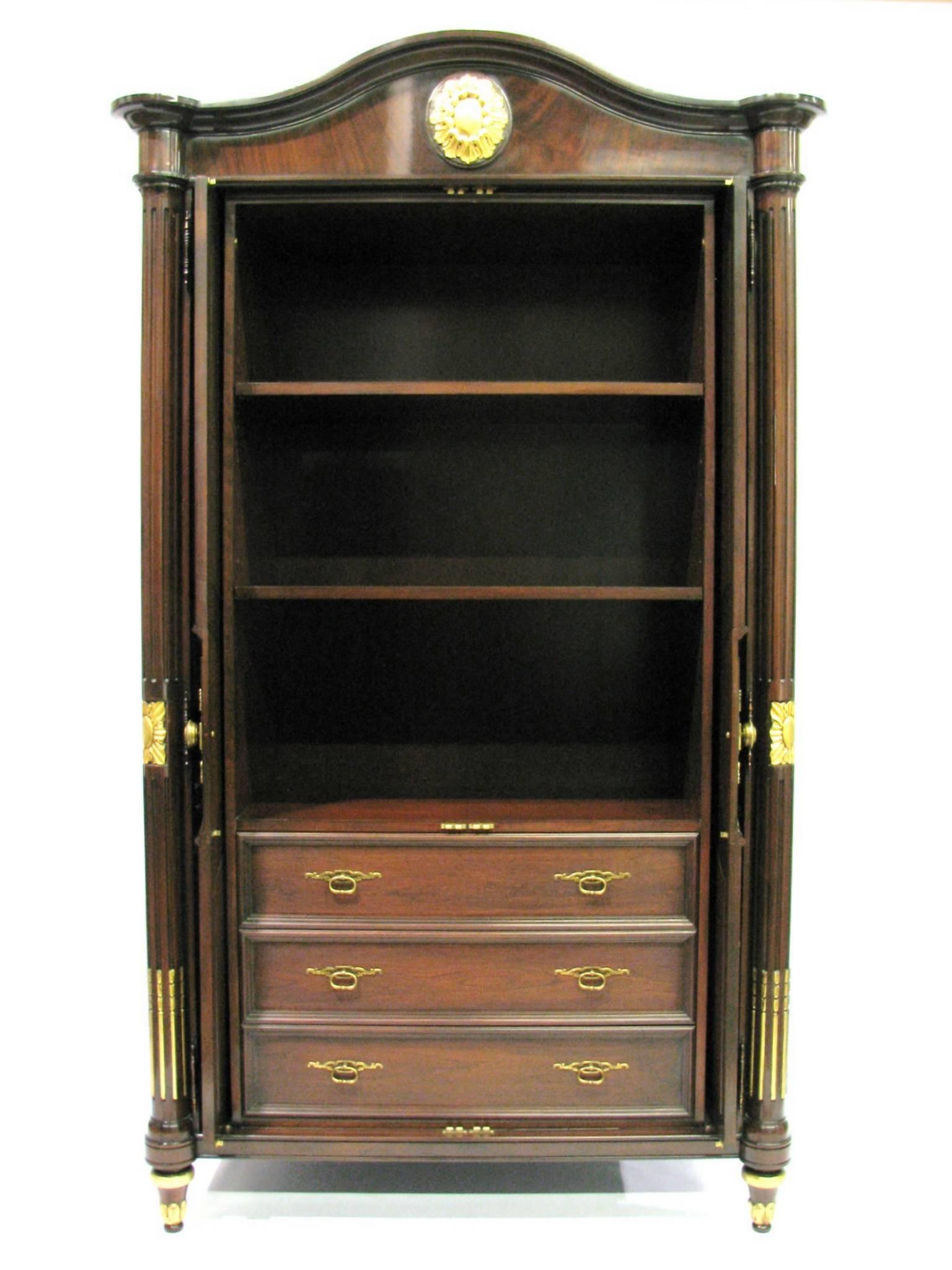 Stunning Karges Louis XVI style armoire. Hand-carved mahogany solids and flame veneer doors. Carved and gilded details. Highly polished finish. Two doors open to reveal three shelves (Two are adjustable) over three drawers. Doors slide inward and