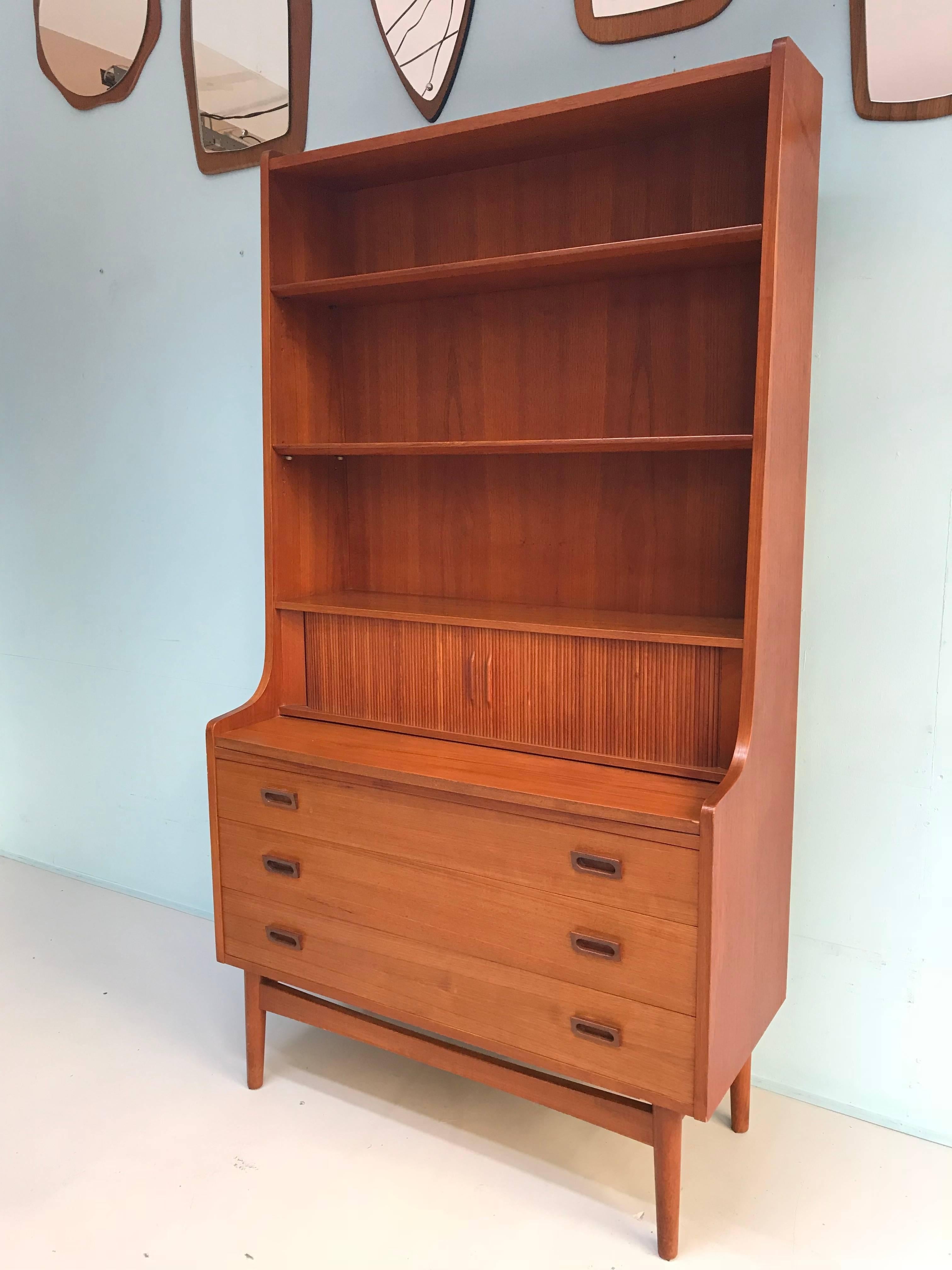 Danish teak midcentury secretaire by Johannes Sorth for BM Mobler with pull-out writing surface, letter storage and small drawers behind tambour sliding doors three height-adjustable shelves and a lower cabinet with three drawers.
Condition: