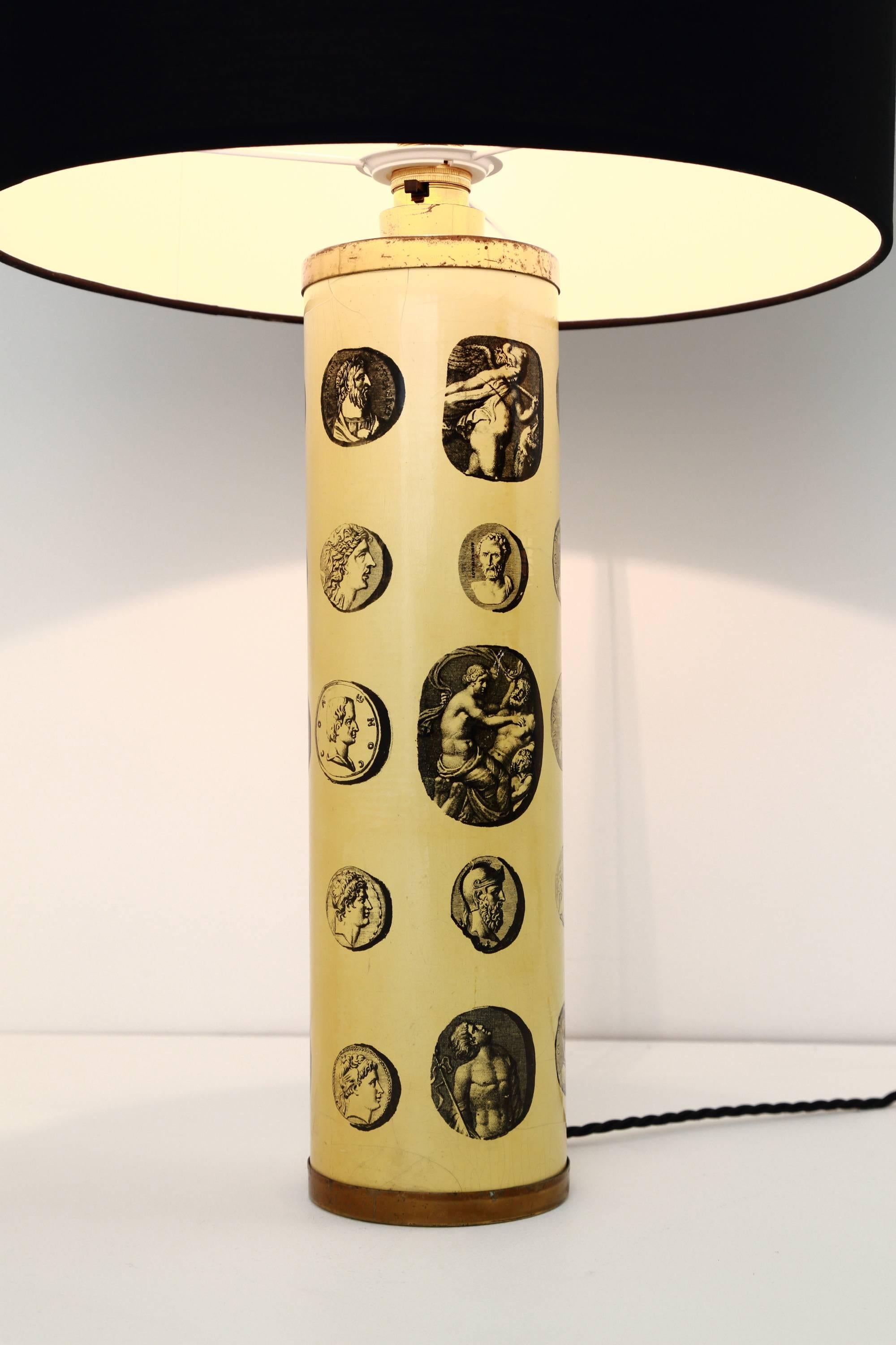 A 1950s ‘Cameo’ table lamp designed by Piero Fornasetti. The lacquered, cylindrical base features transfer images of Classical Roman figures on a parchment colored background. A design Classic from the maestro, that is, Fornasetti.