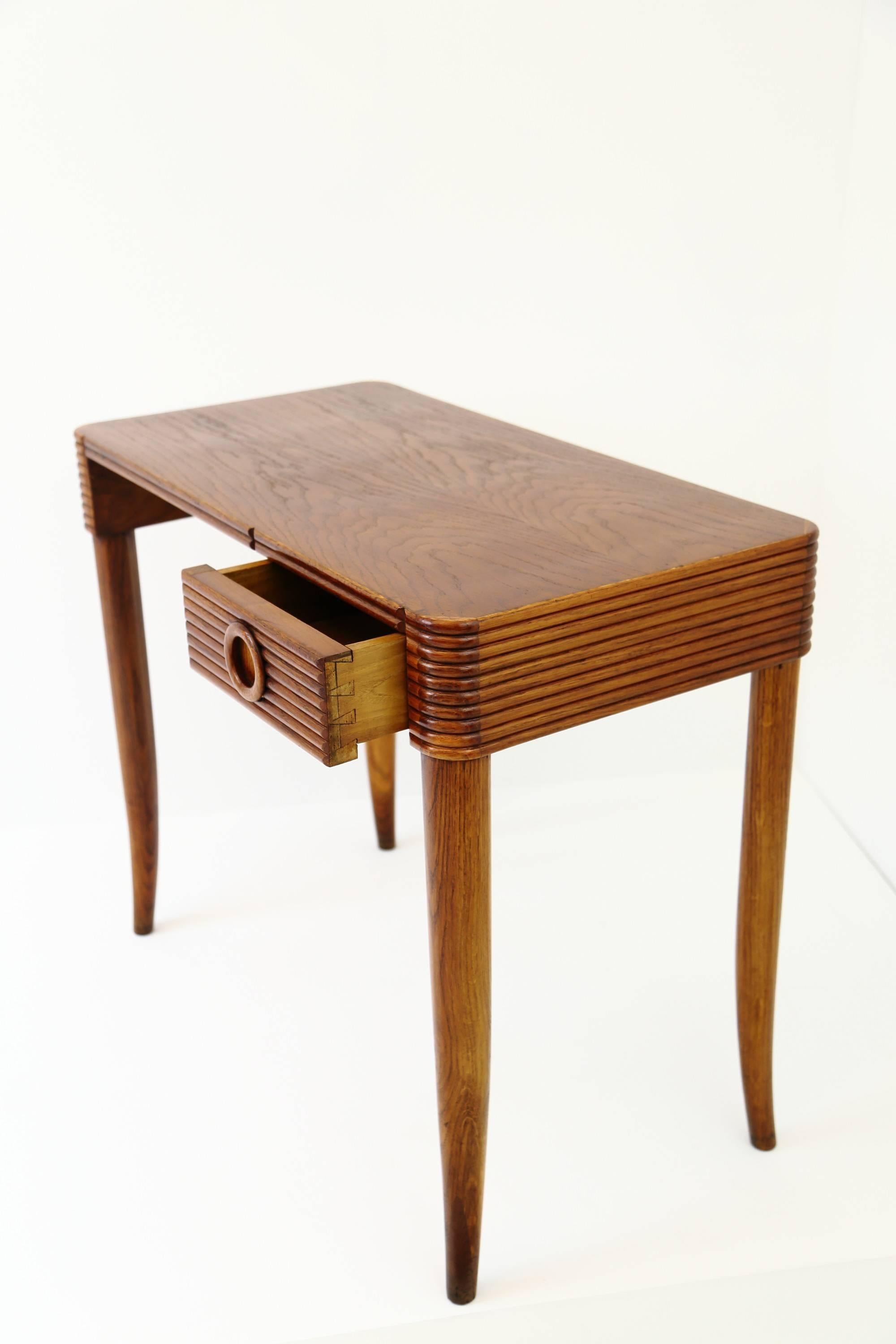 A stained, solid walnut writing desk by the architect and designer Melchiorre Bega. The desk has soft, rounded corners and features beautiful, decorative ‘reeding’ around its perimeter. A useful, small drawer with a carved, circular pull sits on the