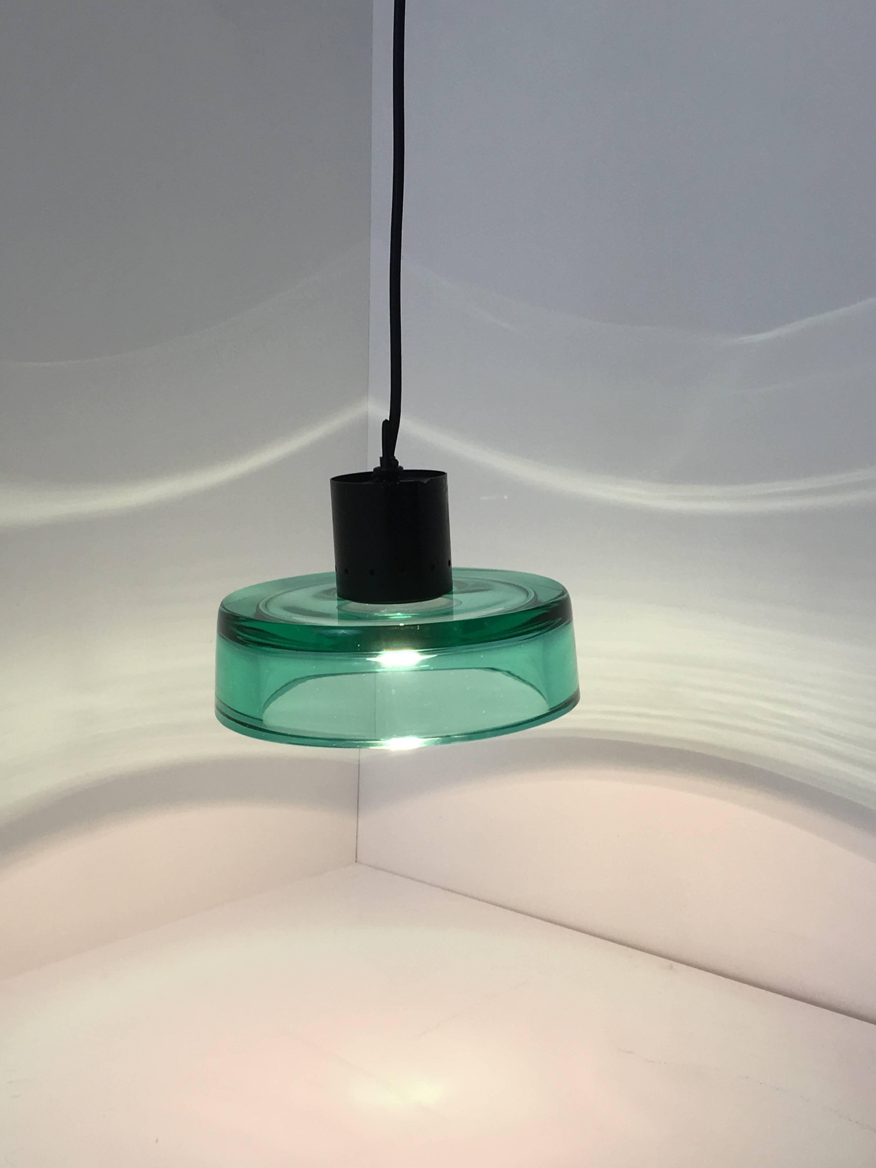 A beautiful, green glass ceiling pendant designed by Flavio Poli for Seguso, Murano. The black lacquered brass fitting is cleverly attached to the solid glass shade and when lit has a clean, luminous quality. Re-wired with black fabric flex.