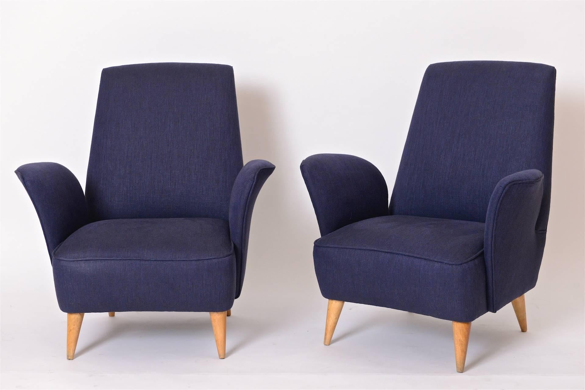 A wonderful pair of 1950s Italian lounge chairs in the manner of Nino Zoncada. These curvaceous Italian armchairs have been completely restored and re-upholstered in a luxurious navy blue linen fabric from Holly Hunt. Sitting on tapered maple legs,