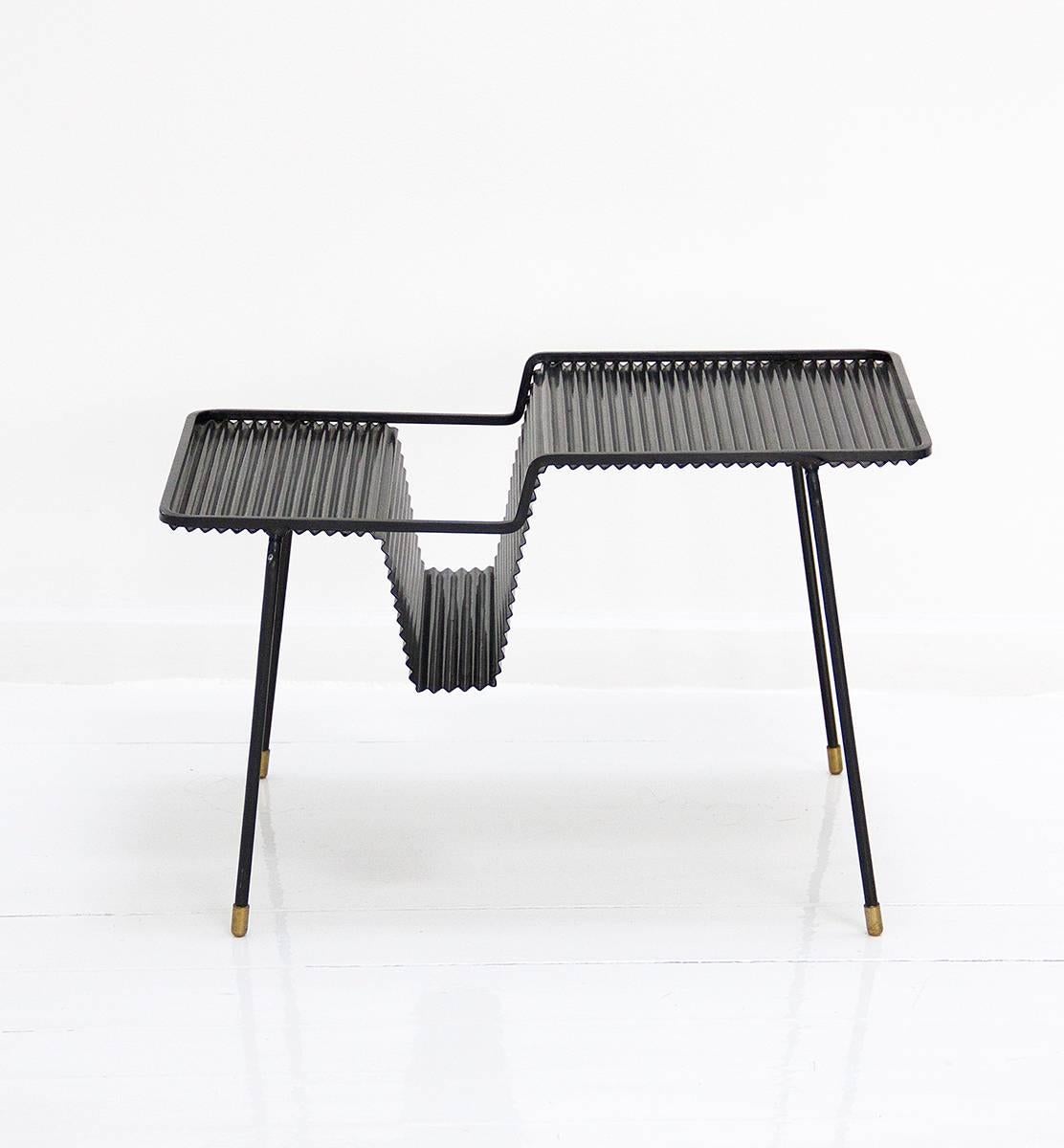 One furniture with two functions; a coffee table and a magazine rack designed by Mathieu Matégot and manufactured by Ateliers Mathieu Matégot. It is made of perforated metal. In original condition and preserving patina. 
Circa 1950,