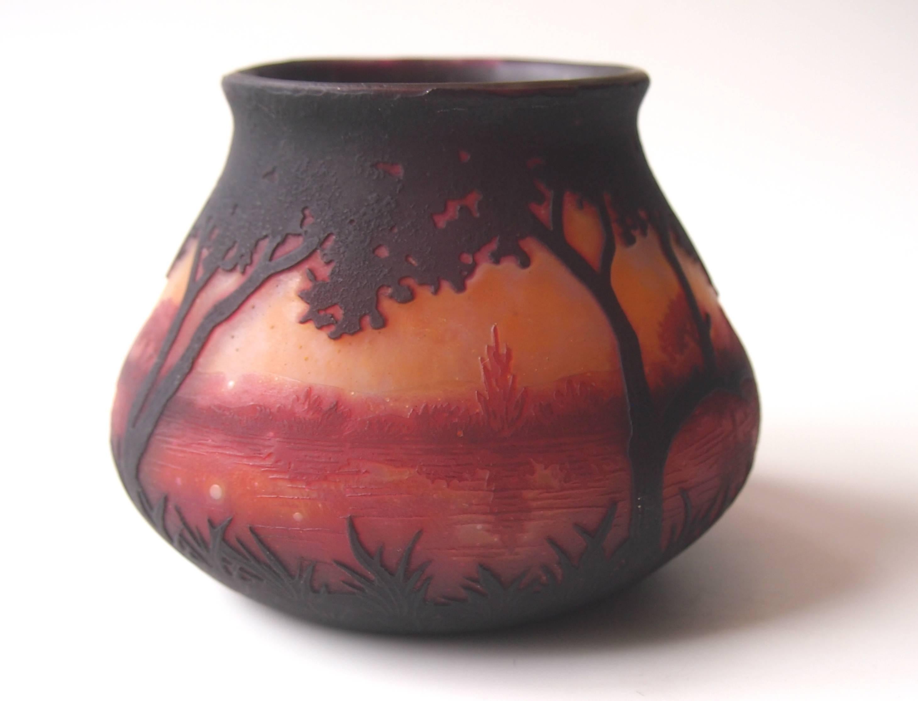 A stunning small, Art Nouveau Daum landscape cameo vase, in orange, browns and blacks depicting a tropical looking aquatic landscape. This vase was a personal gift from Antonin Daum (head of Daum at the time) to a friend and senior Emile Galle
