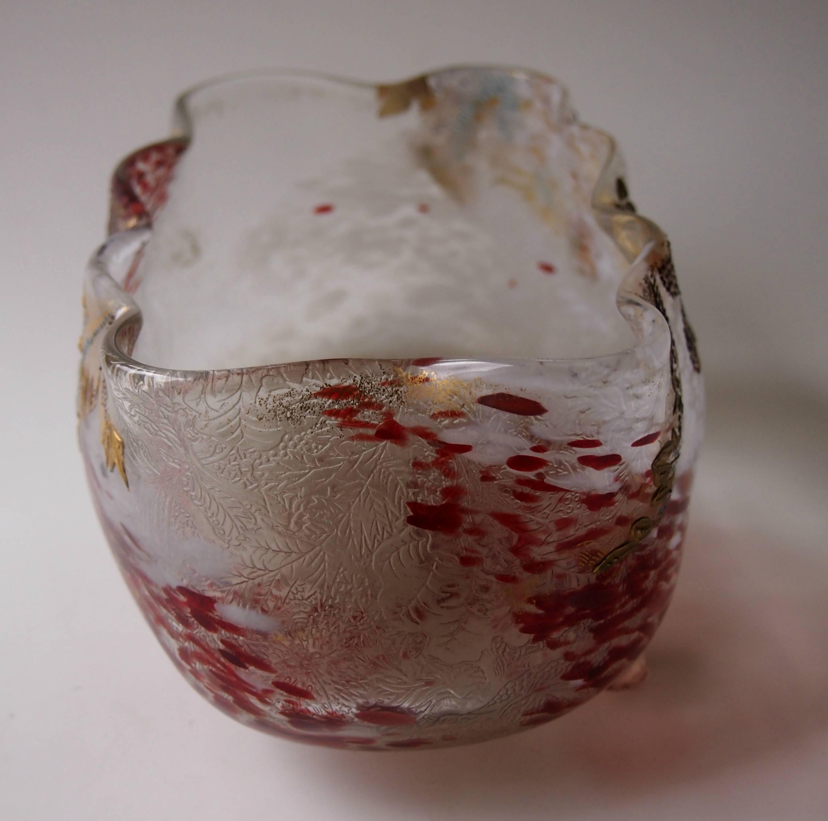 In usual enameled four footed Legras jardinière in a pattern known as 'Pompéi Guilloché' (featured in the newer Legras book p316/7). The glass is largely red and opaque white speckled in clear with a Fine detailed pattern on the inner surface. It is