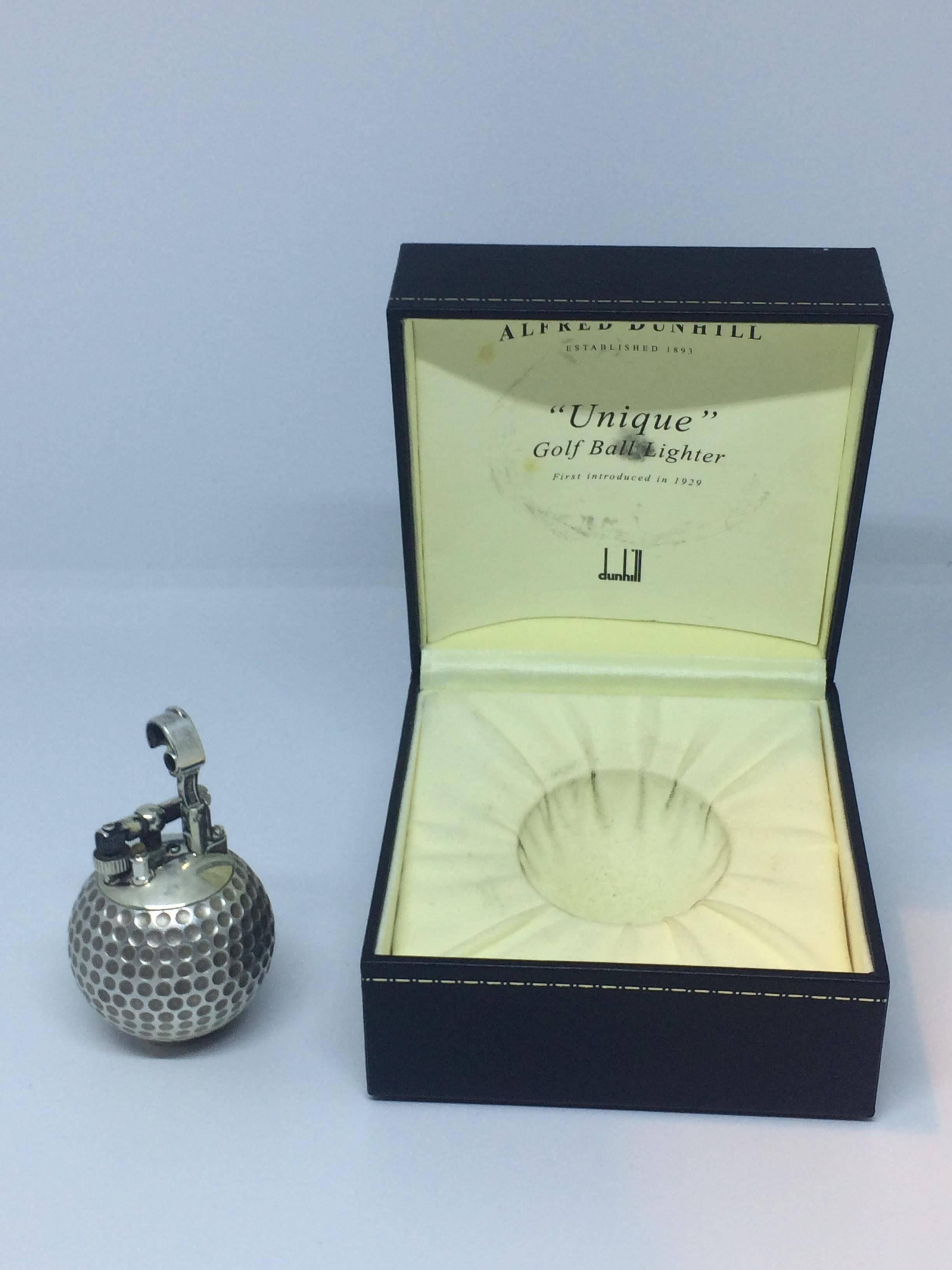 This is a handcrafted sterling silver table lighter in the form of a golf ball by a company named Dunhill. This Classic petrol lighter, with the curved arm was introduced by Dunhill in 1929 and remained a strong part of their collection until the