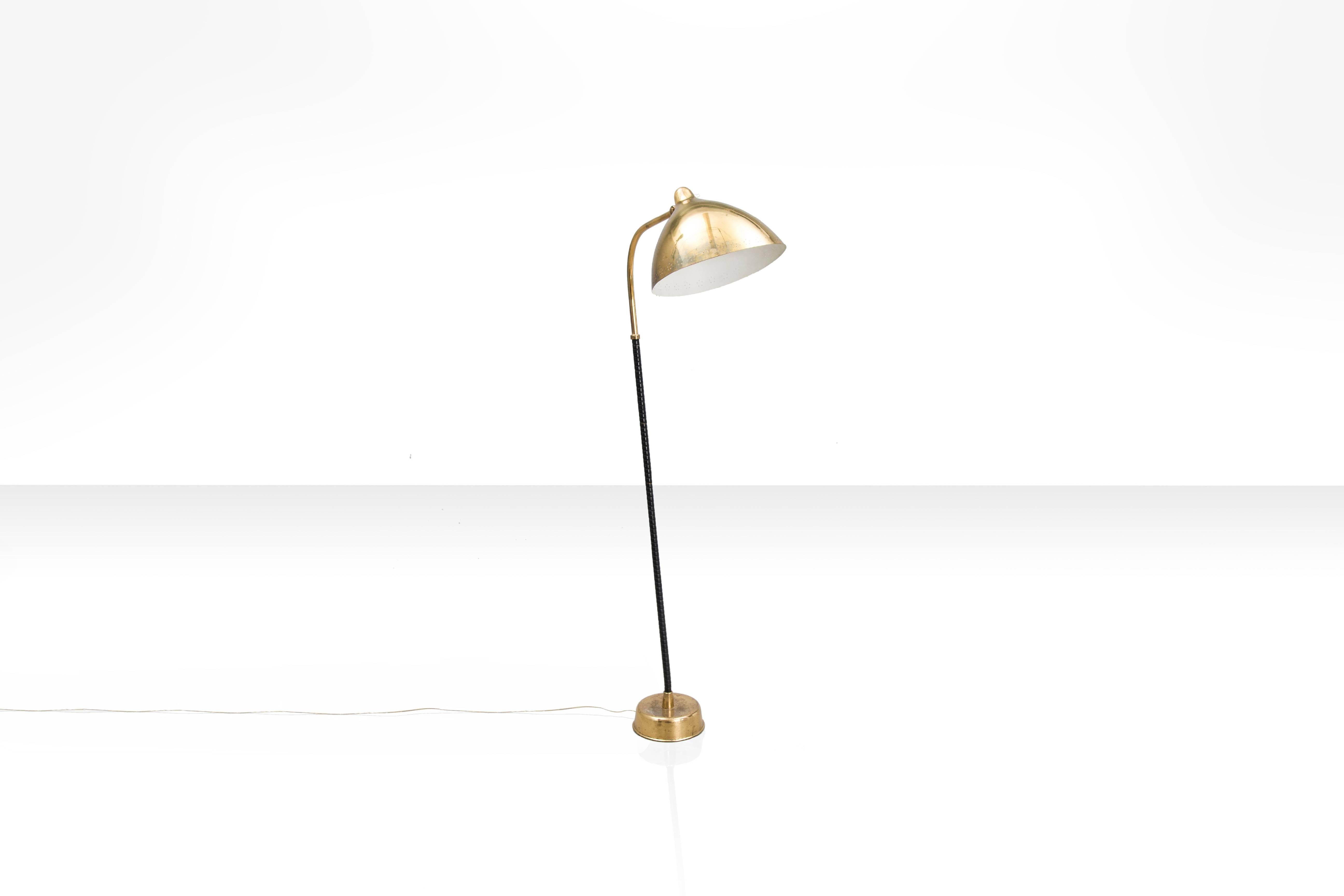 This elegant floor lamp by Lisa Johansson-Pape has a perforated brass shade that is supported by a thin slanted pole wrapped with black leather. This elegant lamp is as beautiful in real life as on the pictures and a timeless classic.

Signed with