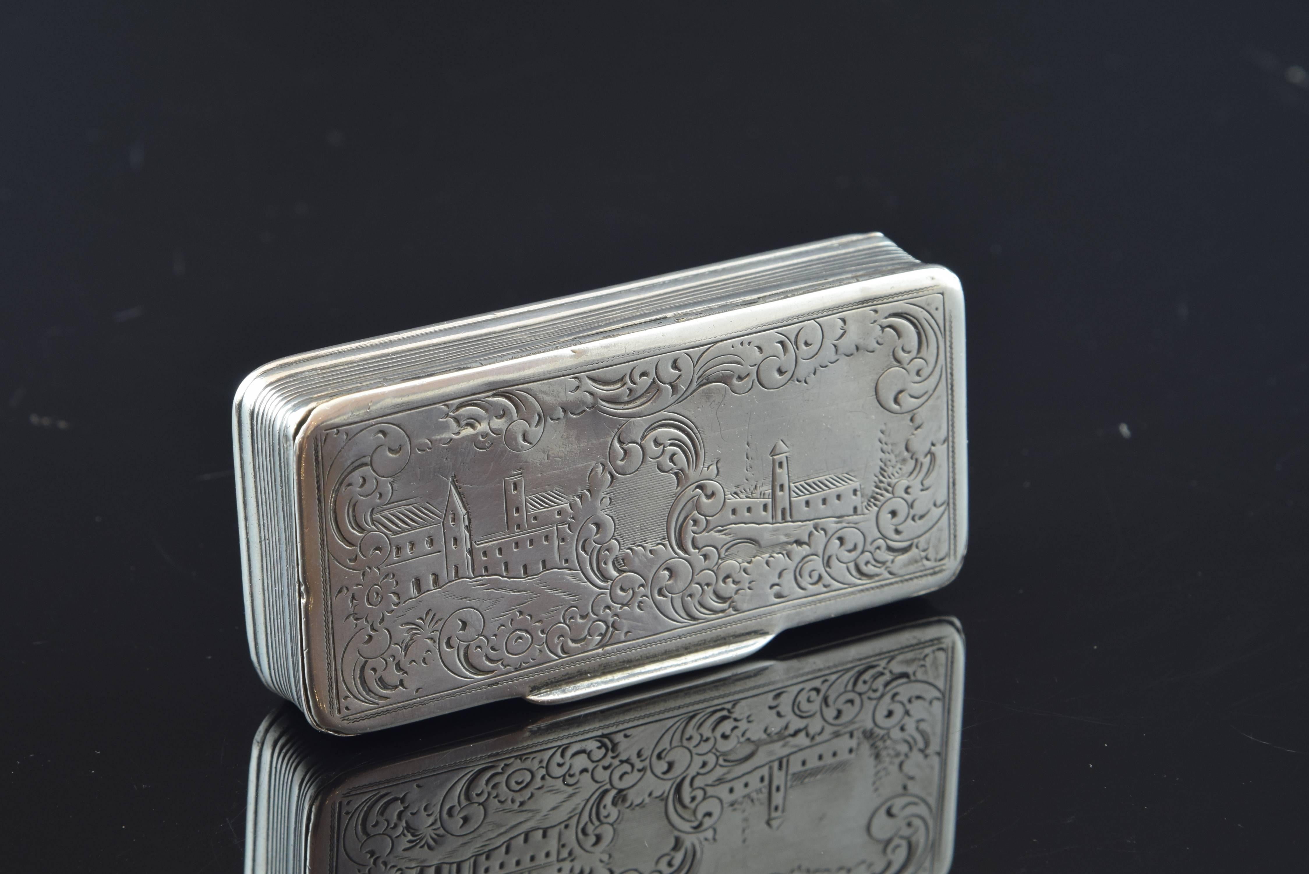 Boîte rectangulaire avec couvercle sur le dessus:: fixé à la base par des charnières:: et décorée d'un paysage simple encadré d'éléments végétaux simplifiés et de formes rappelant le rococo rocaille. Les côtés et la base présentent une série de