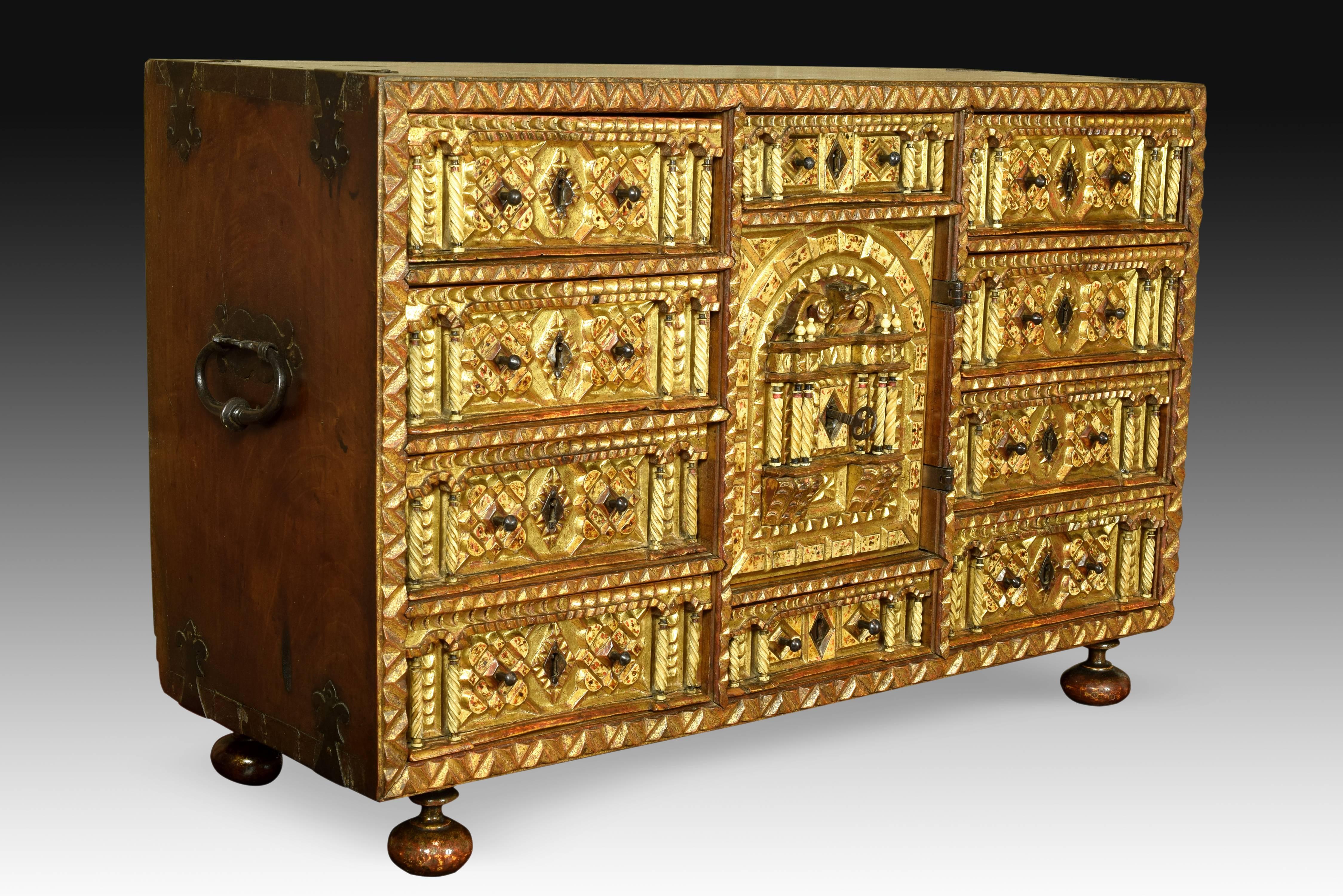 Walnut wood desk with box structure, without front cover whose front appears in view. It has 10 drawers and a central door with drawers in the interior show a decoration of carved wood, gold and with plates embedded bone creating geometric