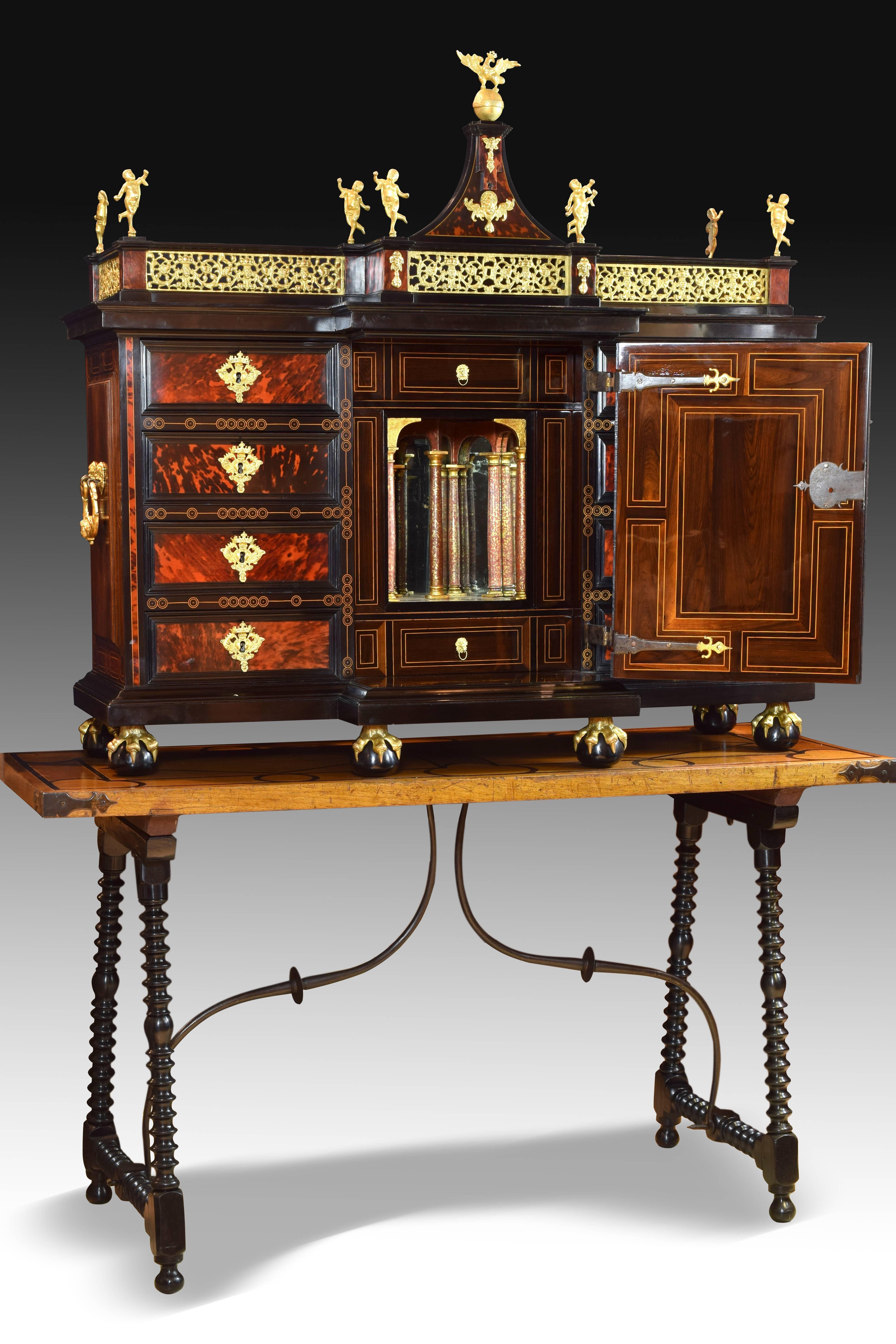Italian cabinet in tortoise shell, wood and gilded bronze, wood of rosewood, lemongrass and iron fasteners. 17th century. Table with walnut board.
Uncovered sample desk located on eight claws with ball and two handles on the sides. The front