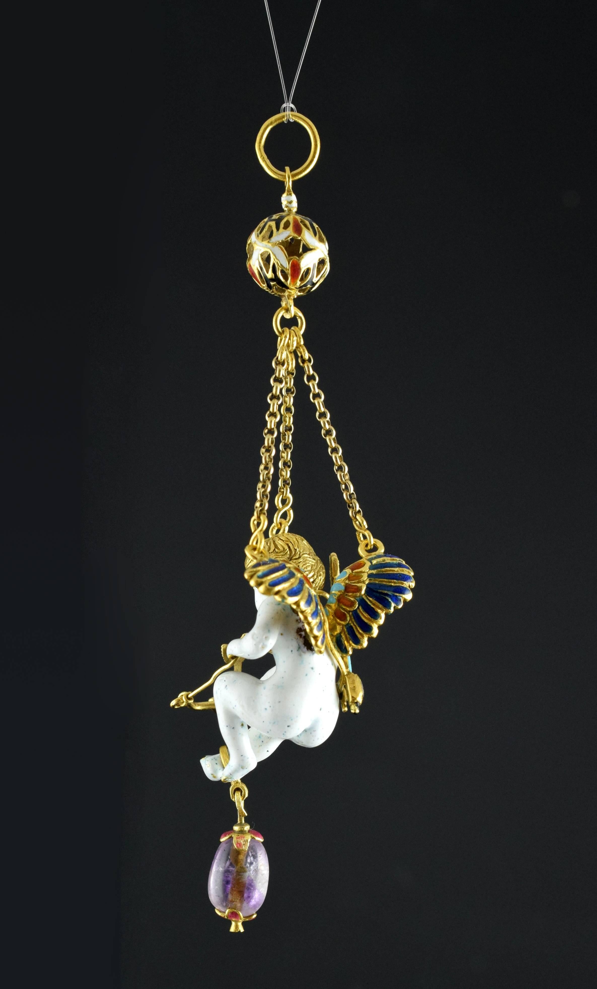 The white human figurine is suspended in the air thanks to three gold chains, which are joined in a perforated ball decorated with red, white and black enamels, from which arises the ring from which the pendant would be hung around the neck. The