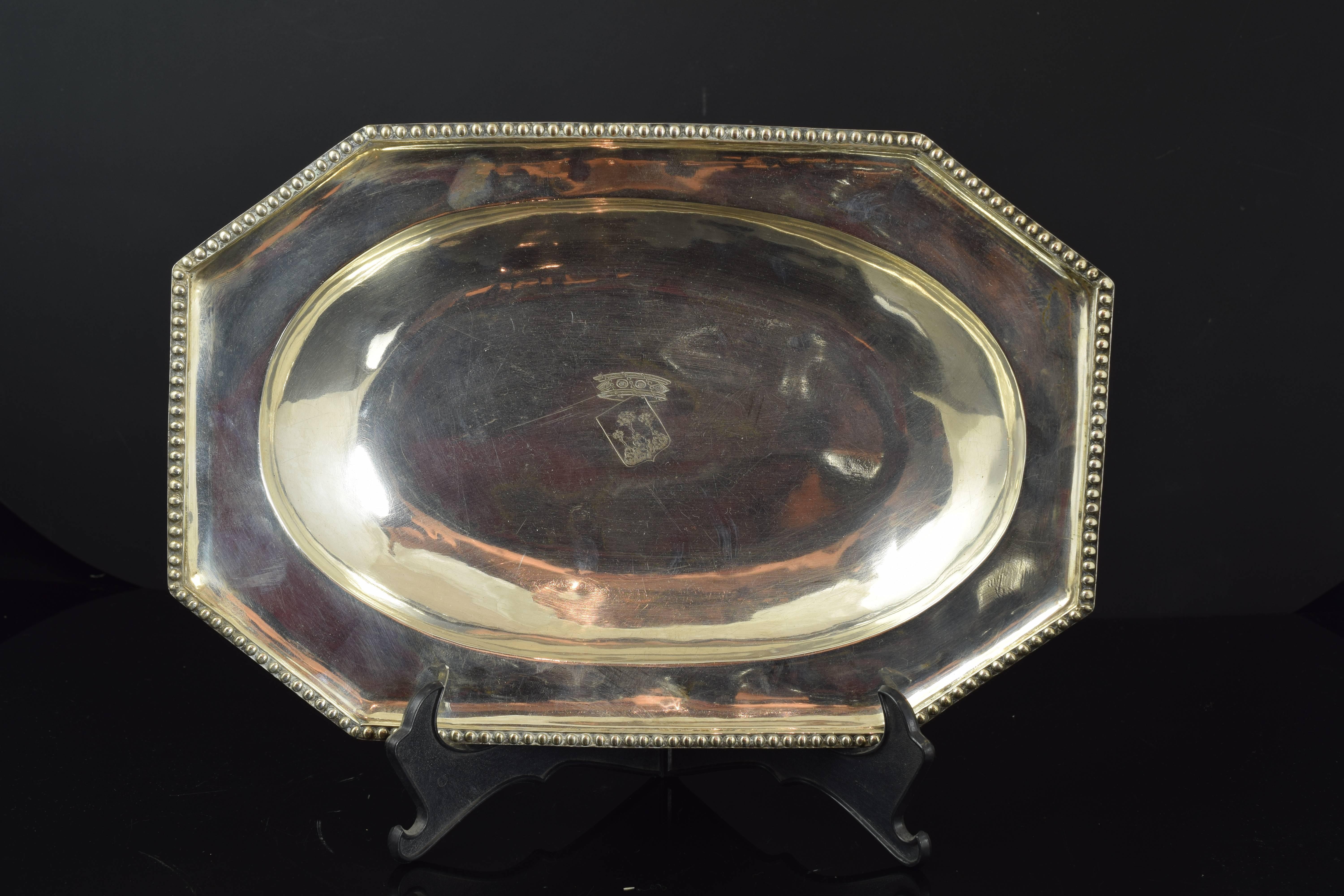 Solid silver tray. Barcelona, Spain, 18th century.
With hallmarks.
Solid silver tray with a octagonal exterior remarked with a thin band of pearls in relief and a oval interior in the upper part of the piece. It also shows and engraved heraldic