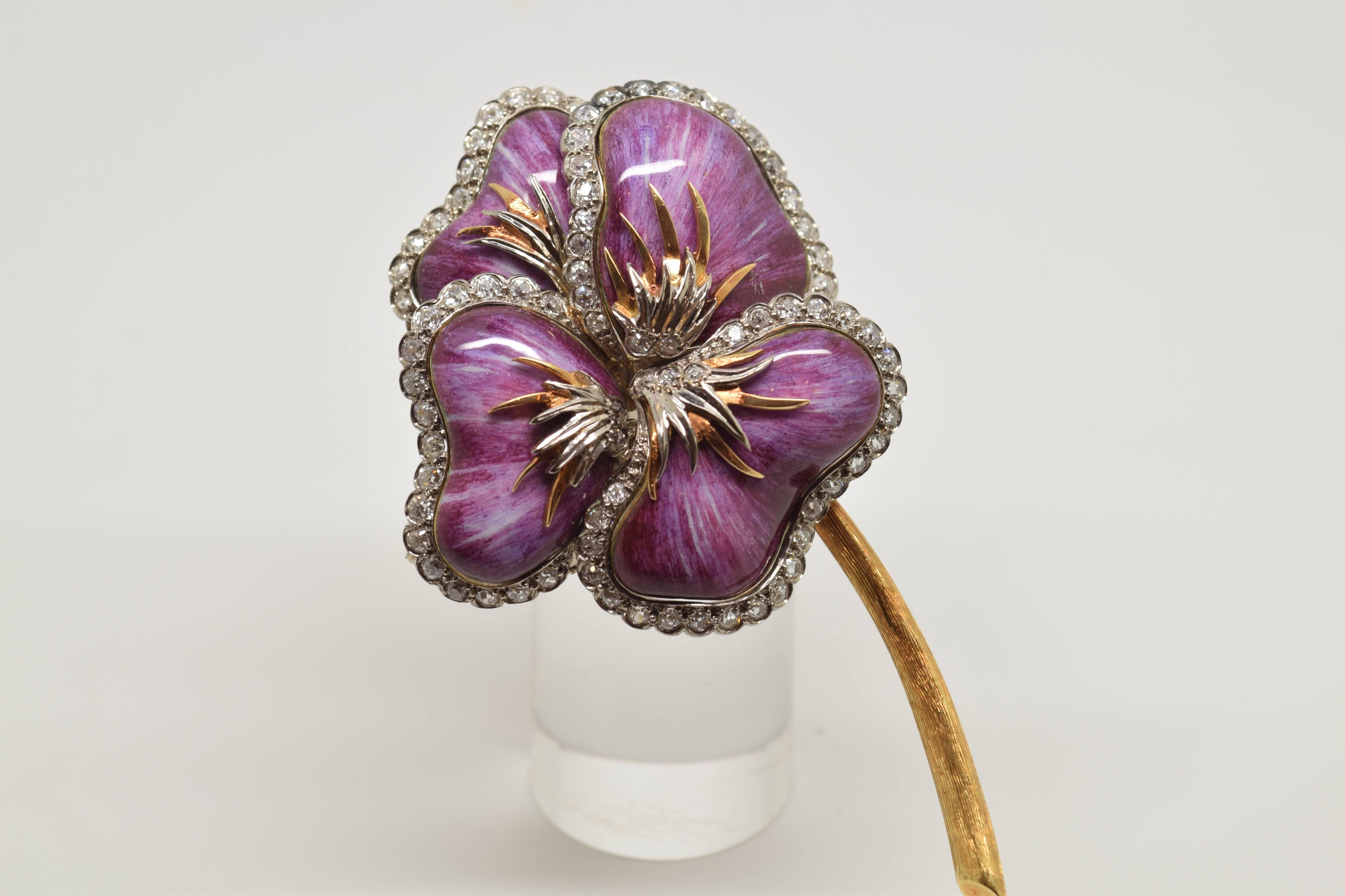 Brooch made in 18-carat gold shaped like a flower. The stem has been left with the gold color, but in a matte finish, while the petals of the flower show a worked composition combining several techniques: the base contributes the color of the flower