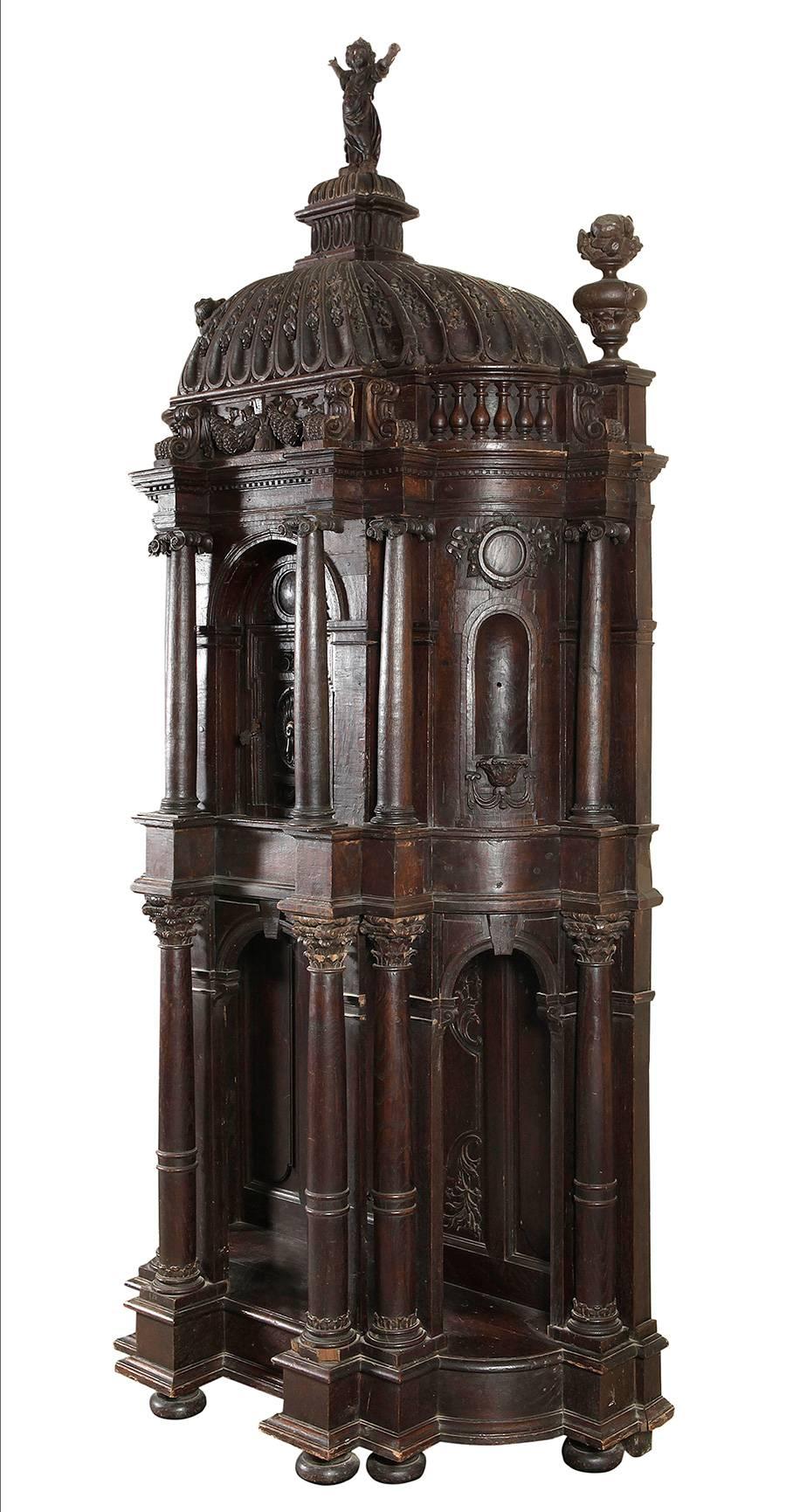 Baroque shrine of architectural structure, entirely made of carved and turned oak wood. Its design follows that of a contemporary architectural facade, with a semi-elliptical plant and organized in two registers, with a cupulated finish with