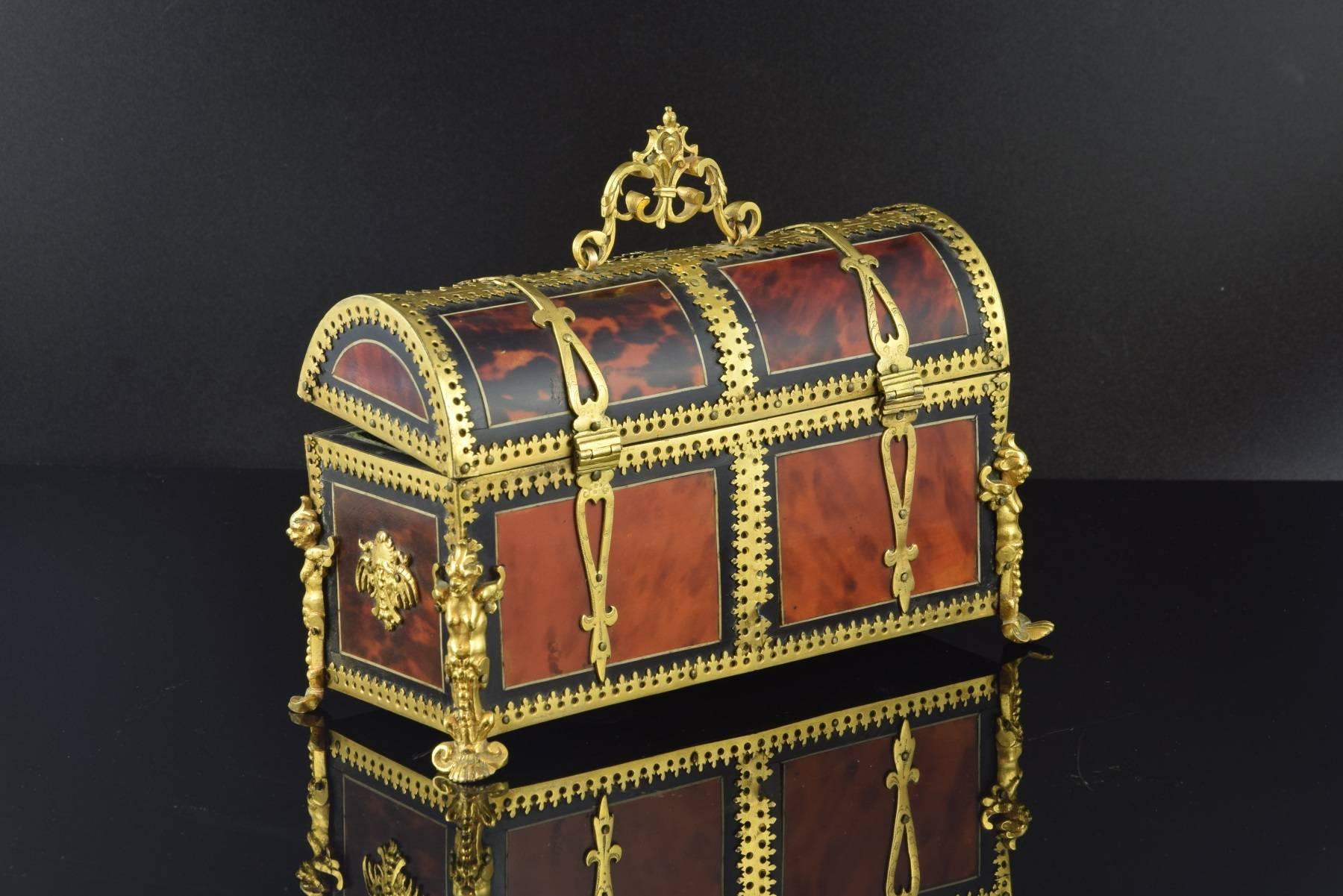 Late 18th century chest
Wood, gold bronze and hawksbill.
Chest made at the end of the 18th century, with a wooden structure composed of a prismatic base and a vaulted cover, articulated by two hinges extended to the outside with motifs and