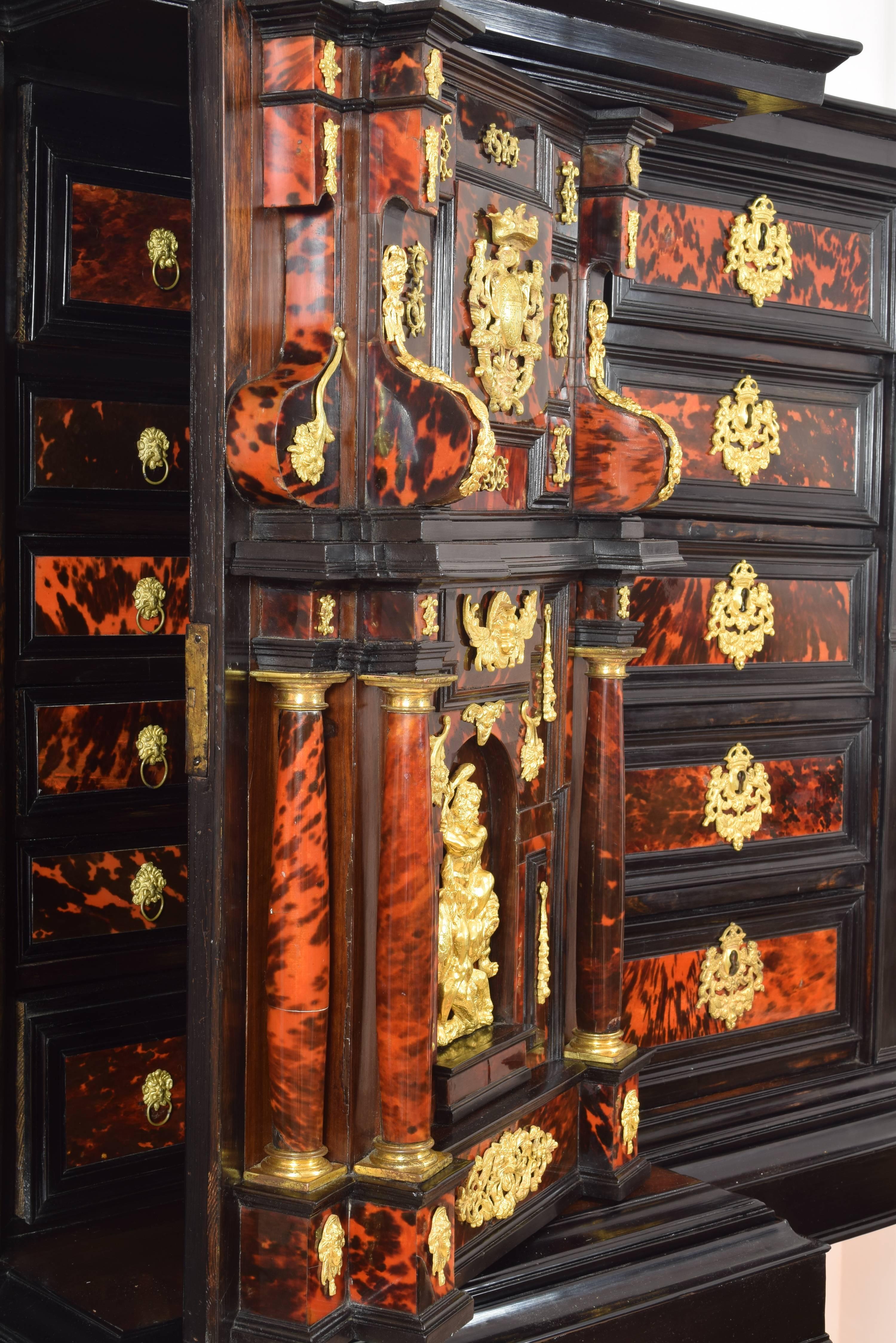 Uncovered sample desk made of wood, with the central part advanced and highlighted with a double chapel of architectural composition. Each of the sides has five drawers with the front decorated with tortoiseshell and an elaborate golden bronze lock