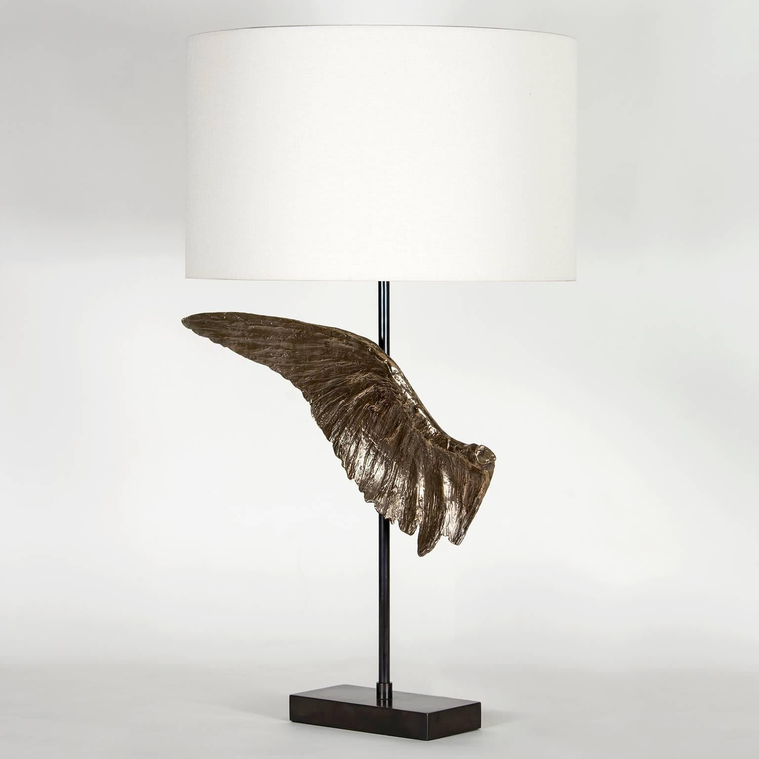 The Voltaire table lamp consists of a cast bronze wing sculpture inspired by the past and present using age old and modern techniques to create each piece. There is a left and right wing available and each has its unique details and slight