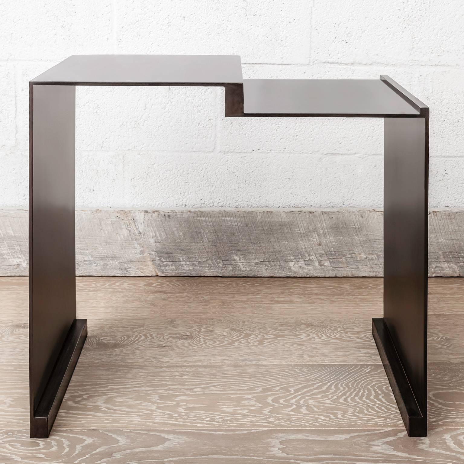 The Roque side table evokes a warm modern elegance with simple lines and solid materials. The body structure is composed of a blackened steel plate in  various segments that create a minimalist sculptural form. It is offered with or without a solid