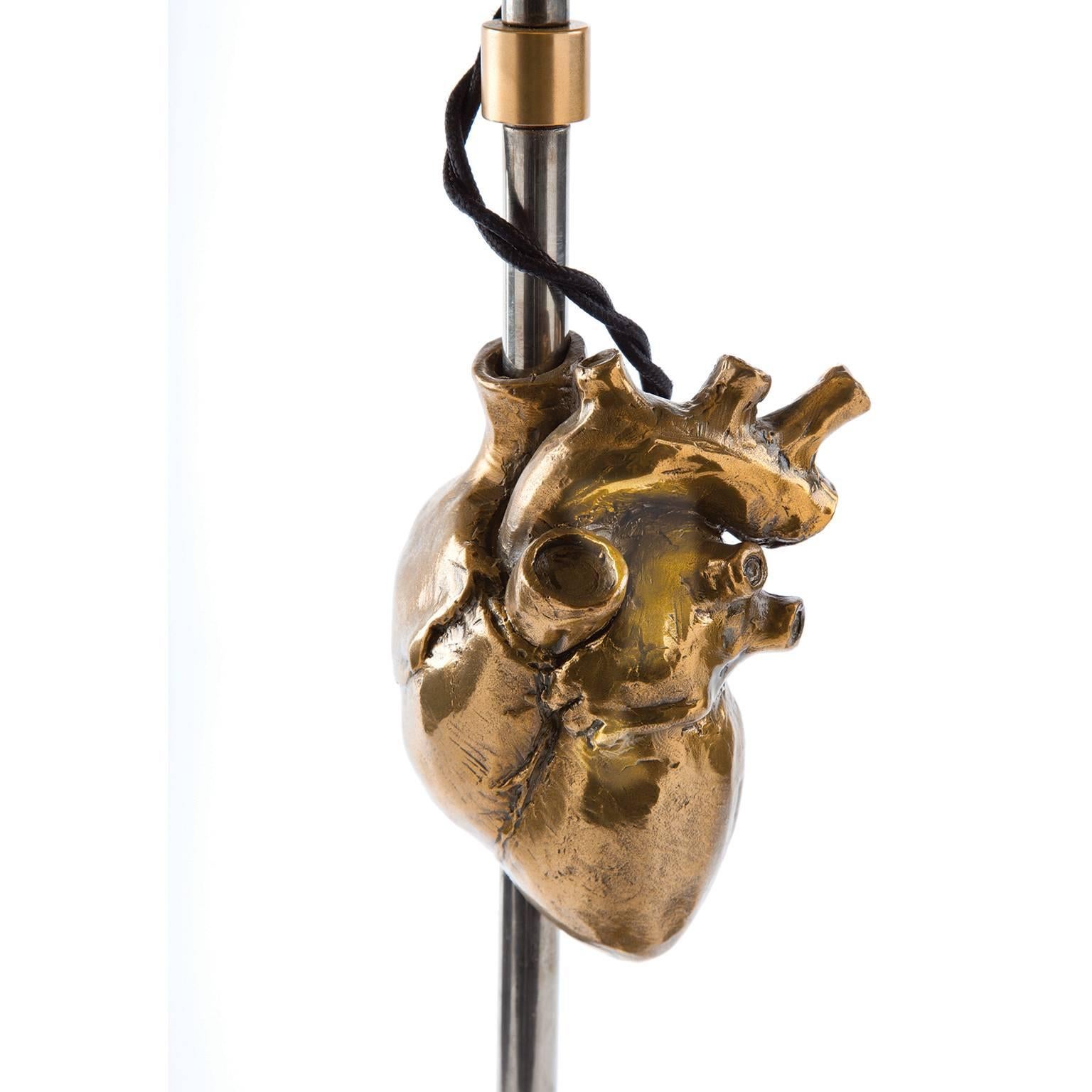 The Kardia lamp is composed of a cast bronze 'human heart' and base (shown with a gold patina) and the body and hardware are solid brass (shown in a light antiqued nickel plating). It is available in various metal finishes and combinations as well