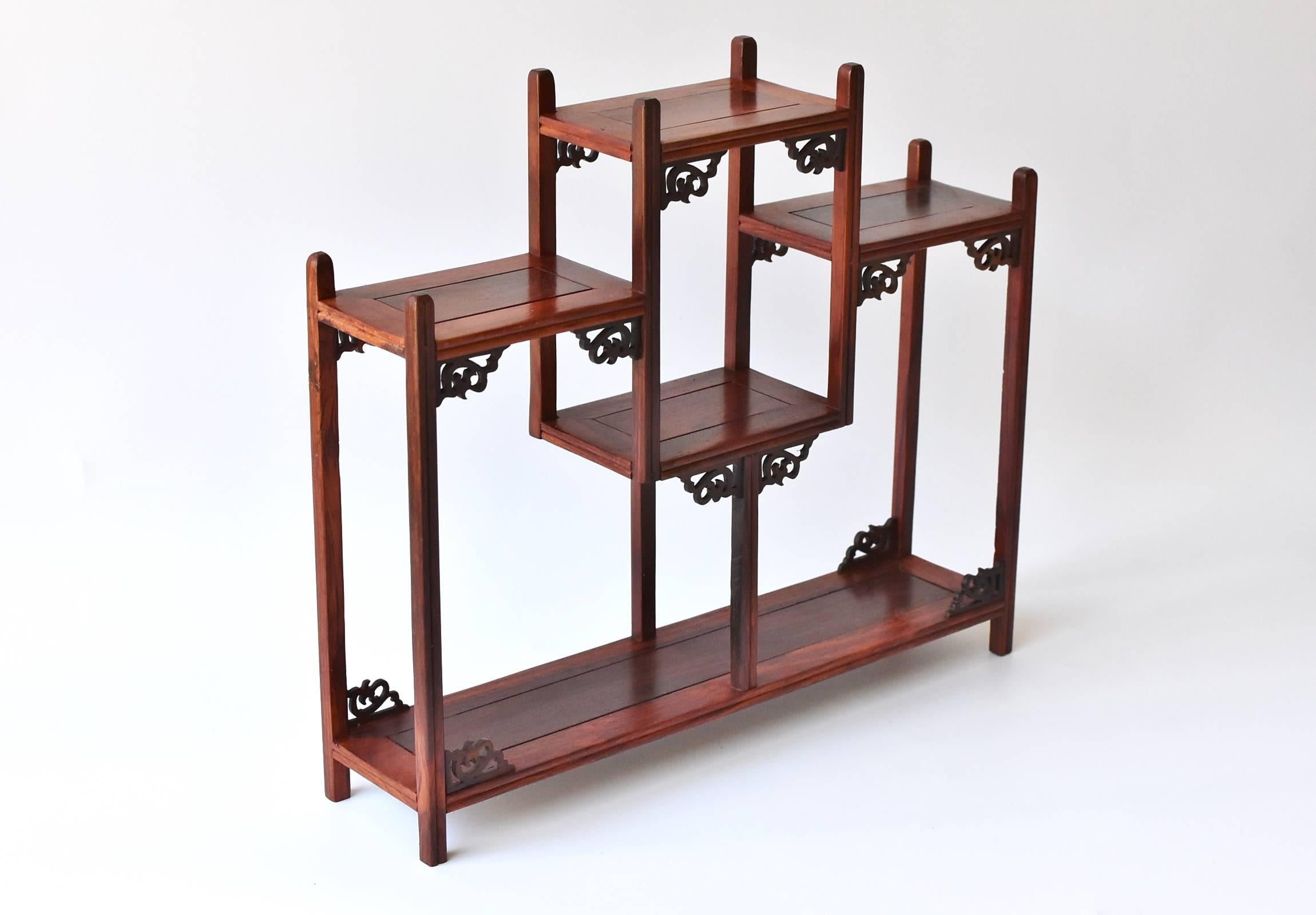 A beautiful mini display case made of Chinese Hua Li wood. 

This exquisite piece features six shelves for displaying small items such as jade carvings and snuff bottles. Nice delicate carved scrolls decorate the corners, adding interest and beauty.