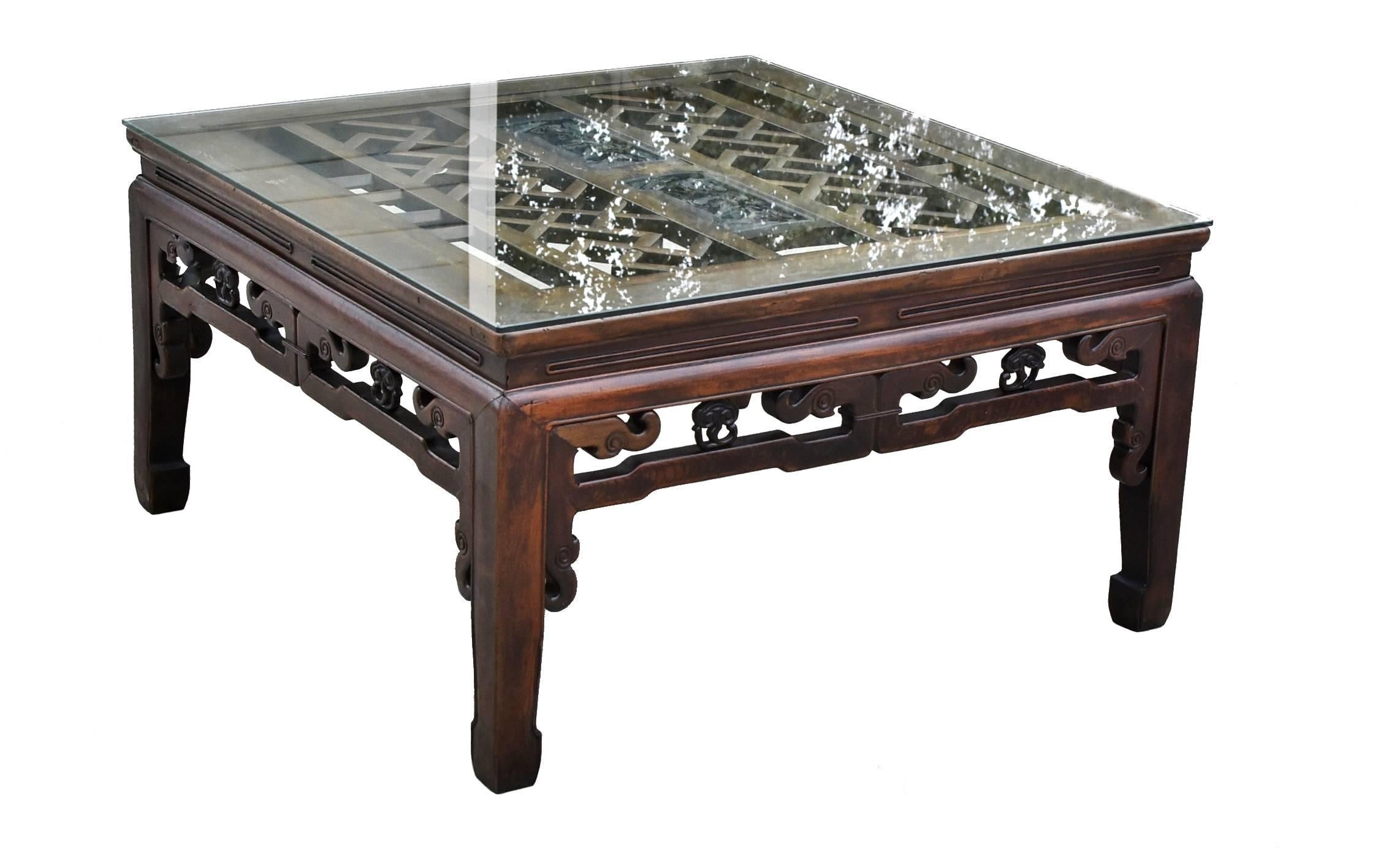 A beautiful square coffee table that is inset with a large antique carved screen. The table is typical of Southern Chinese style with scroll works and Lin Zhi, a herb medicine that symbolizes good health and long life. The screen depicts pine trees