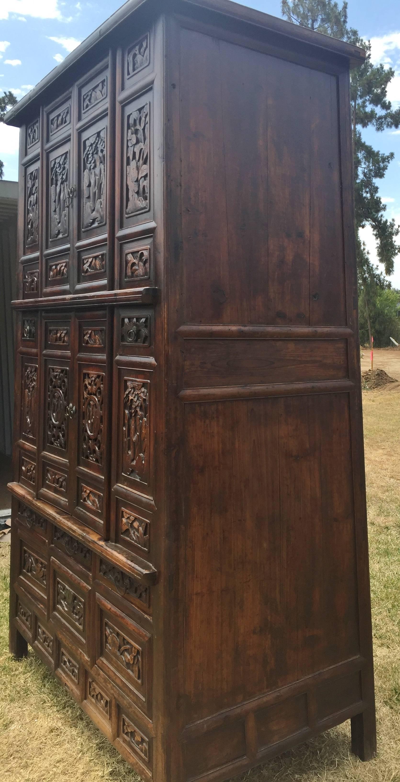 A monumental, fully carved Chinese antique cabinet. At nearly 8 feet tall, this supersized cabinet stands like a giant. Carvings of floral, foliage and a couple in the garden balance out the massiveness of the cabinet, giving it an artistic touch.