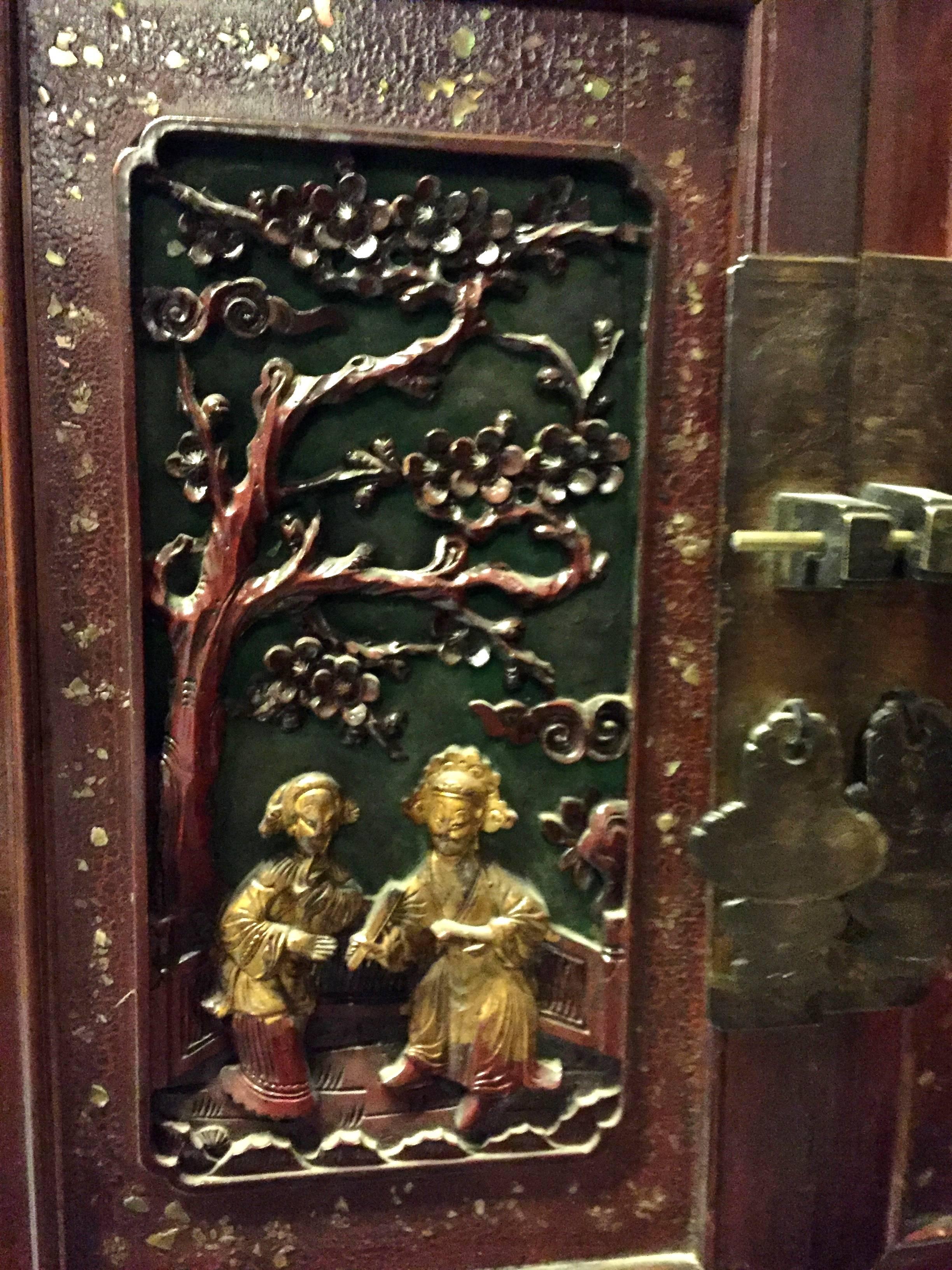 Beautiful cabinet features 4 finely carved panels depicting a courting couple. The trees indicate 4 seasons. Mother-of-pearl encrusted frameworks and gilded figures highlight the theme. Carved butterflies decorate the corners of the cabinet with