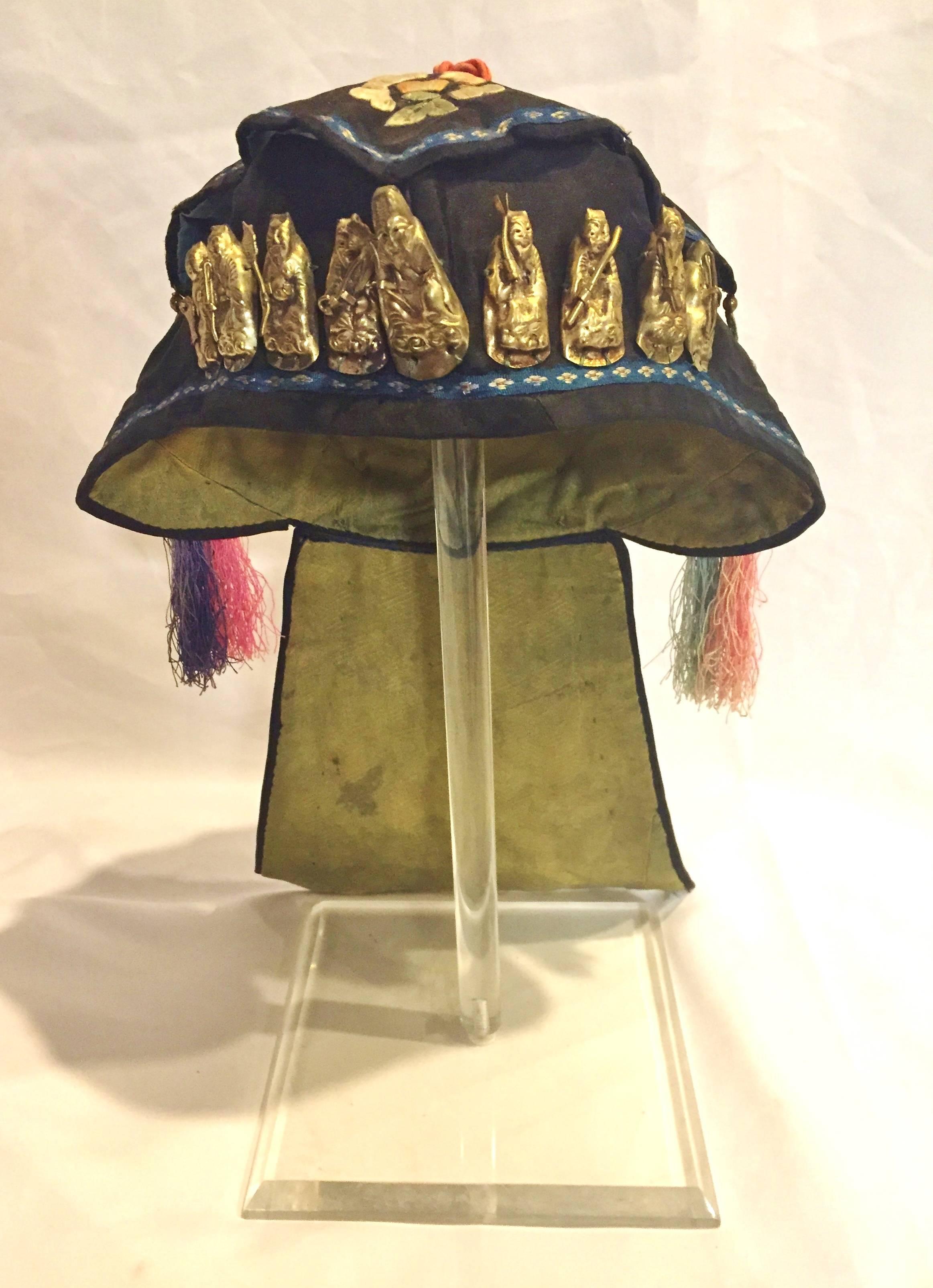 An antique silk embroidered hat with full set of silver ornaments. This exquisite hat belonged to a wealthy family's little prince. It is finely embroidered with peonies, which are symbols of prosperity. Two pairs of silk tassels decorate the sides