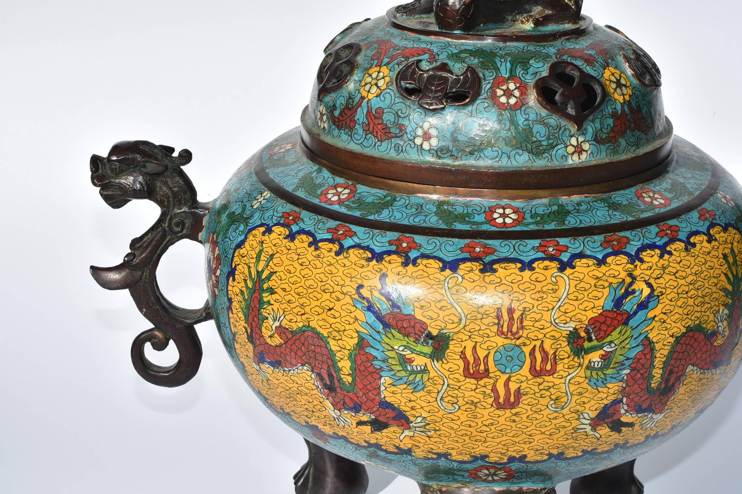 A giant cloisonné incense burner. 

This is a very substantial bronze cloisonné piece. It features a foo dog as a finial and three beast motif bronze legs. A pair of bronze dragons adorn the sides, adding elegance to the large censer. The use of