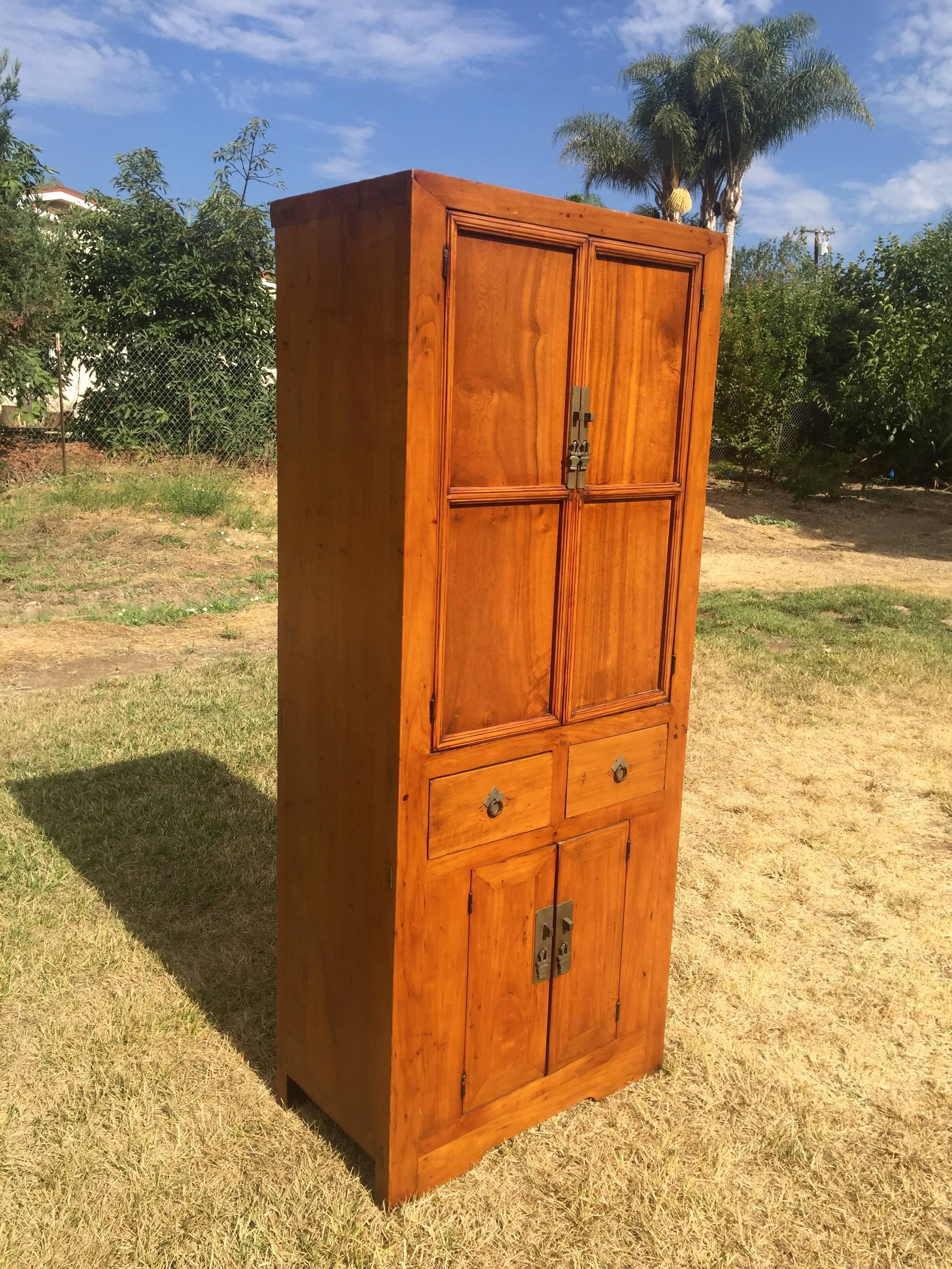 A natural finish narrow chest from northern China. 

This cabinet has the desirable narrow design, making it very versatile as a linen cabinet, bookcase or small wardrobe. The choice of wood is a fine one. A natural, honey tone finish showcases